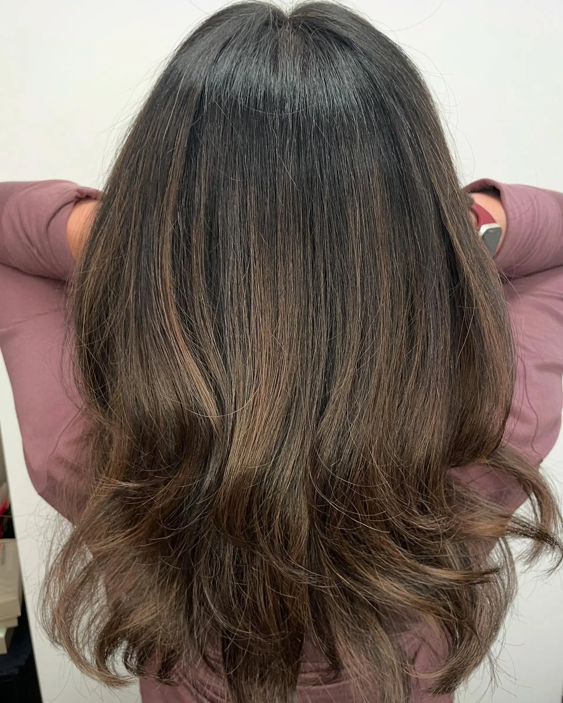 Long dark brown hair cut with soft cascading layers and styled with curled, bouncy ends. 1
