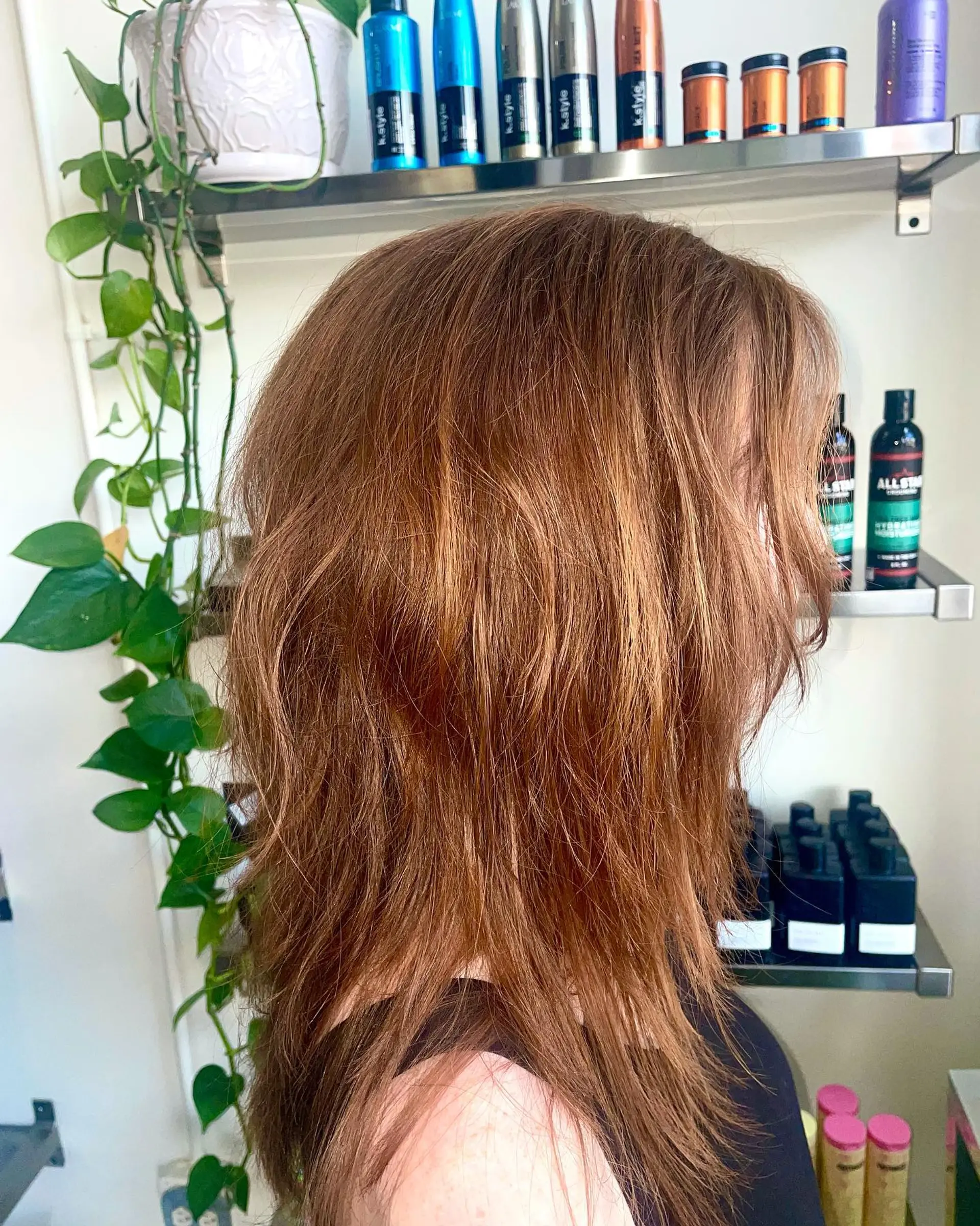 A textured medium-length wolf cut with piecey, feathered layers in a warm auburn tone. 1