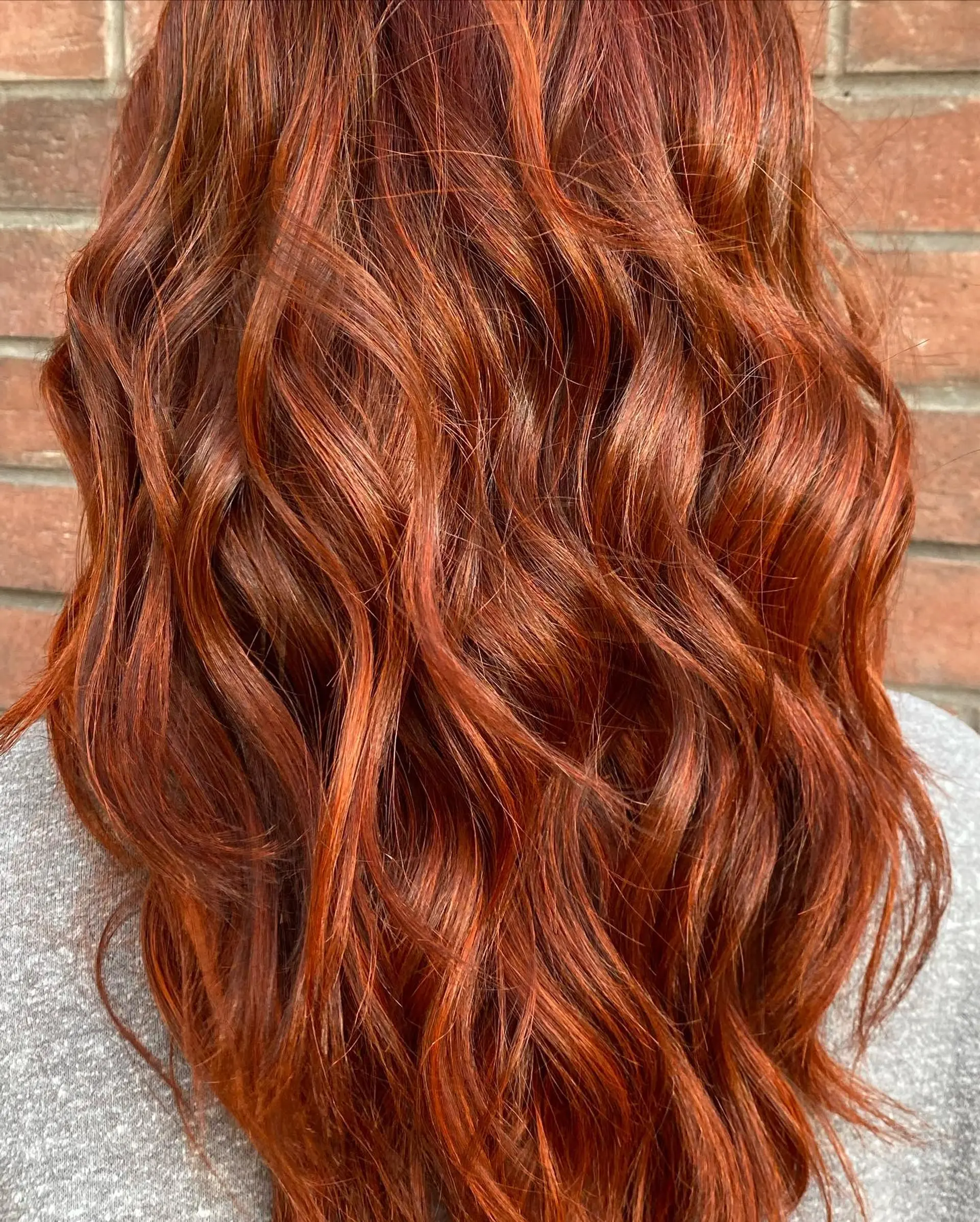 Vibrant, multi-dimensional copper-red hair styled into loose, textured waves. 1
