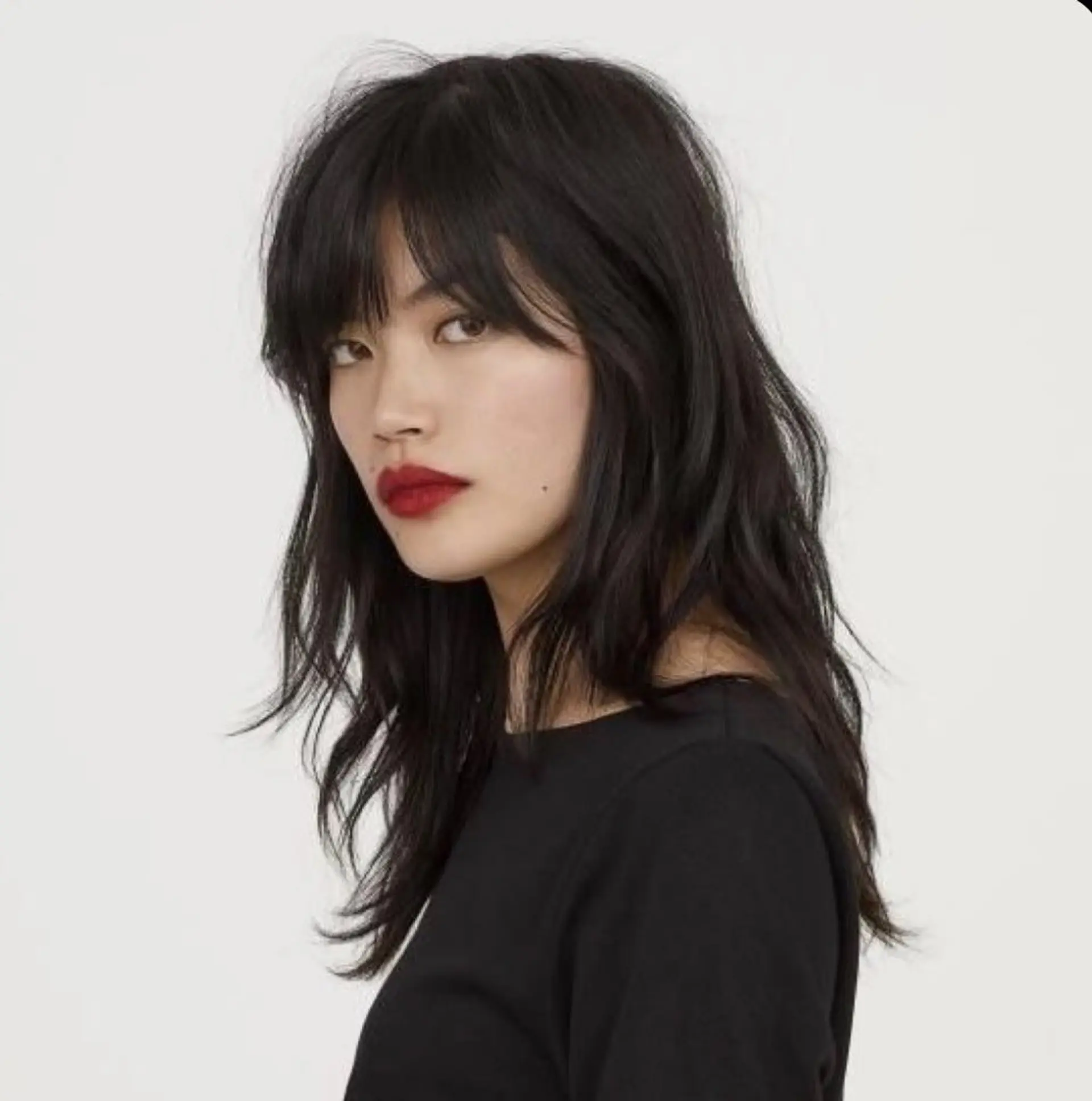 A medium-length textured shag haircut featuring eyebrow-grazing fringe and soft, wispy layers. 1