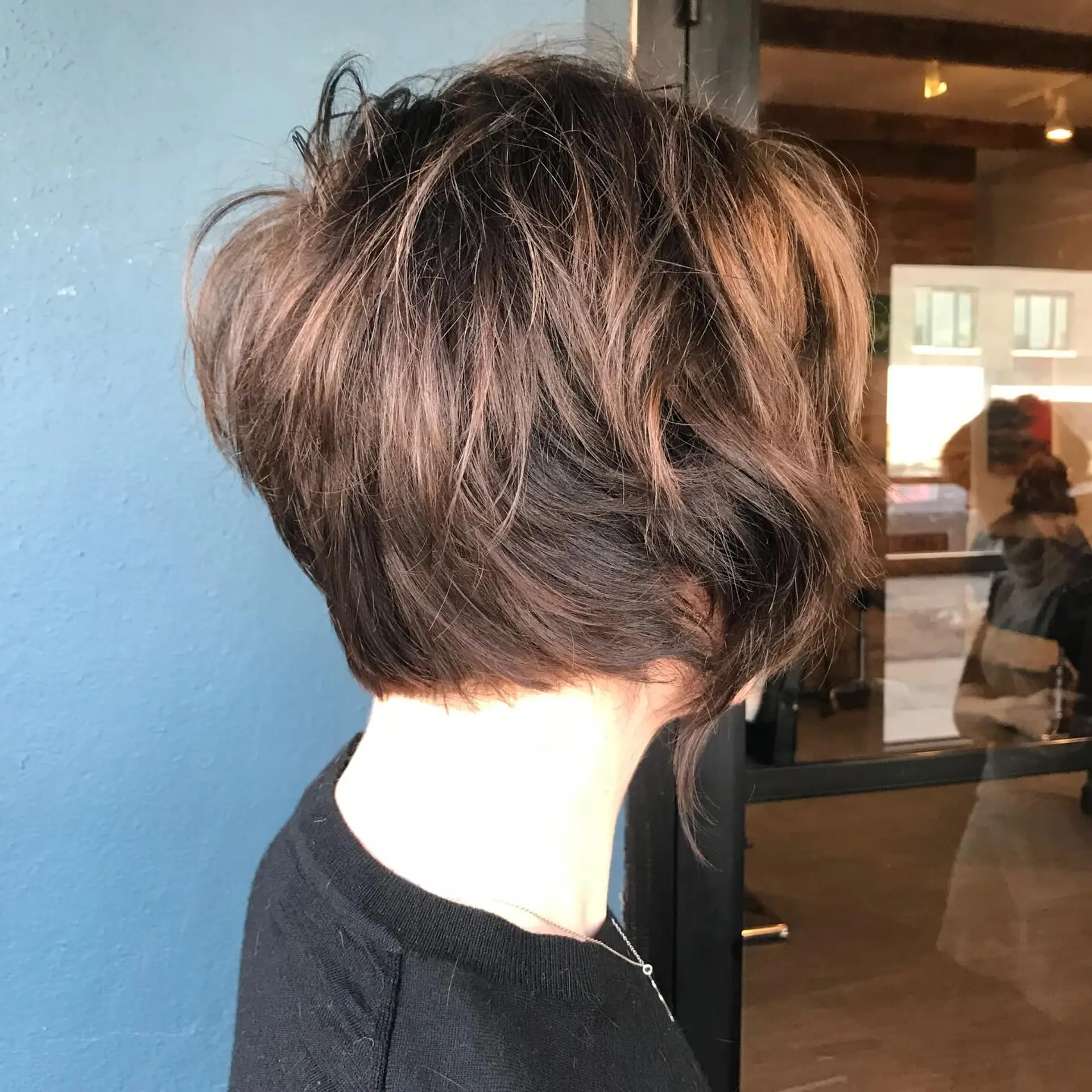 A textured razored bixie cut with tousled layers and dimensional chocolate brown tones. 1