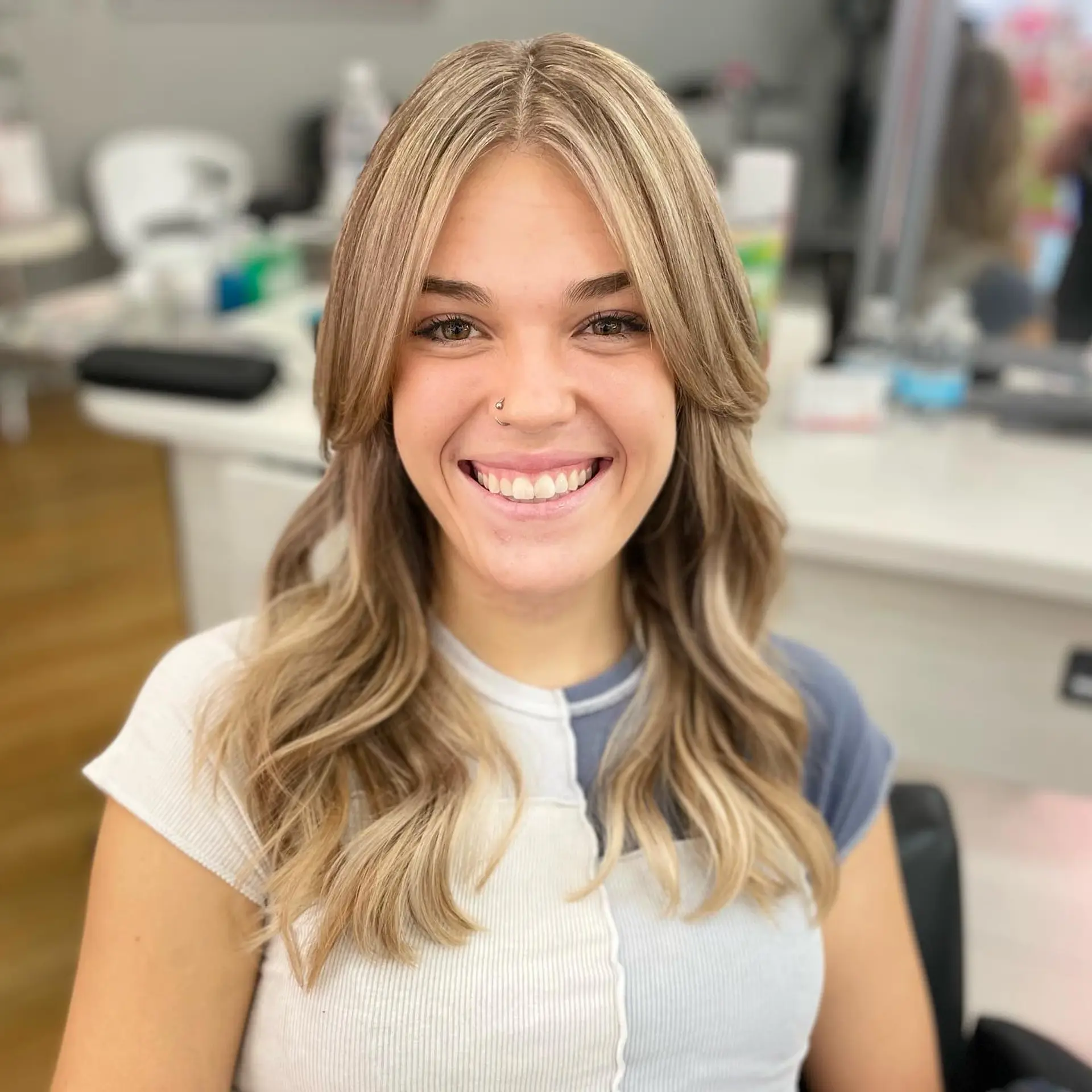 Long dimensional blonde hair styled with soft, parted curtain bangs and loose, face-framing waves. 1