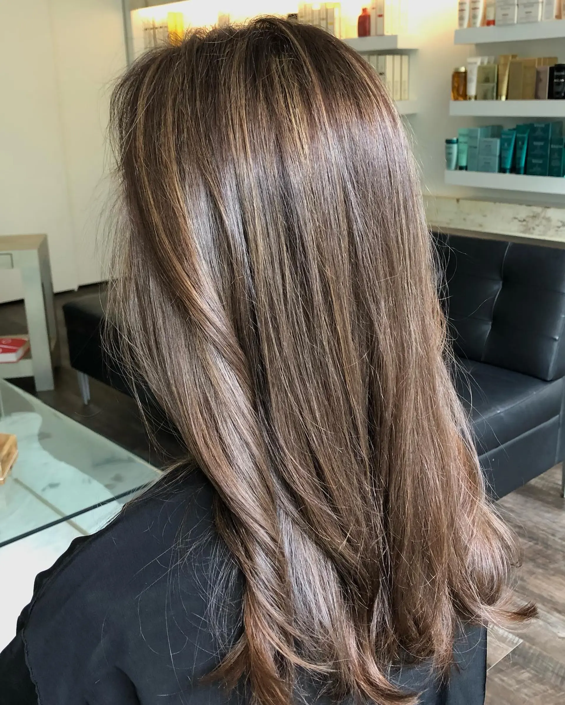 Long dimensional brunette hair with soft highlights and lowlights styled in a smooth blowout. 1