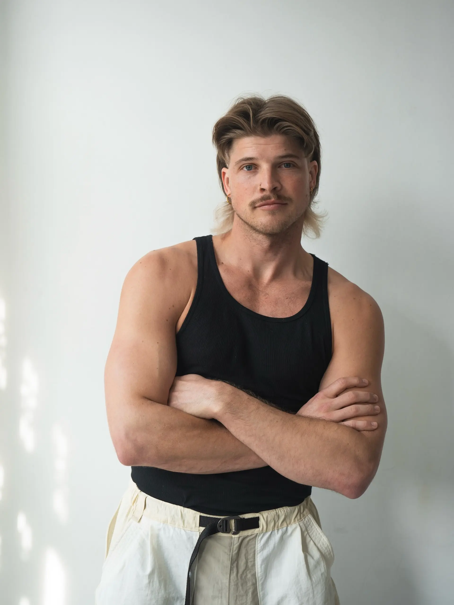 A modern textured mullet styled with volume on top and swept-back sides, featuring contrasting light blonde ends at the nape. 1