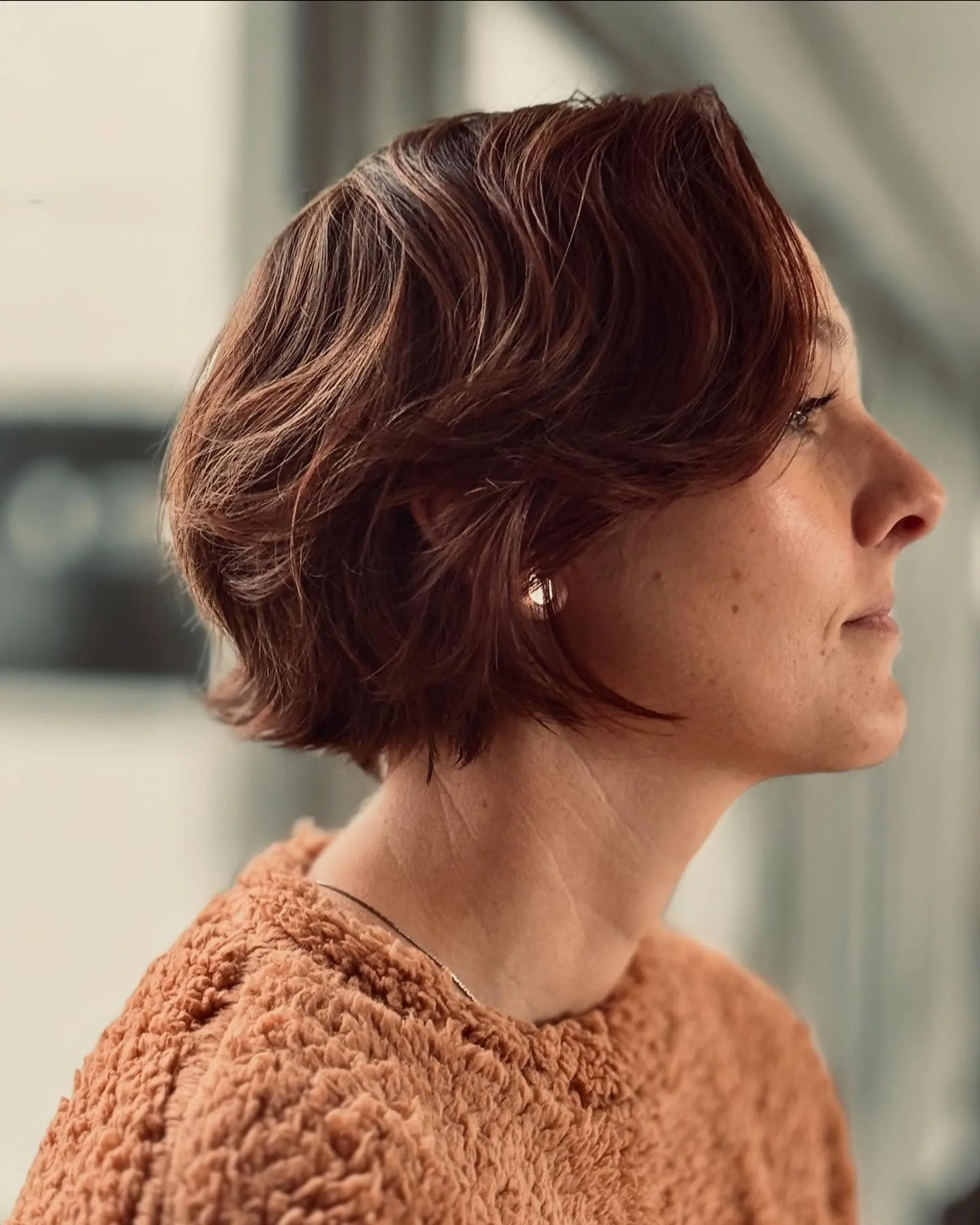 A textured chin-length wavy French bob with soft razored layers and a side-swept fringe. 1