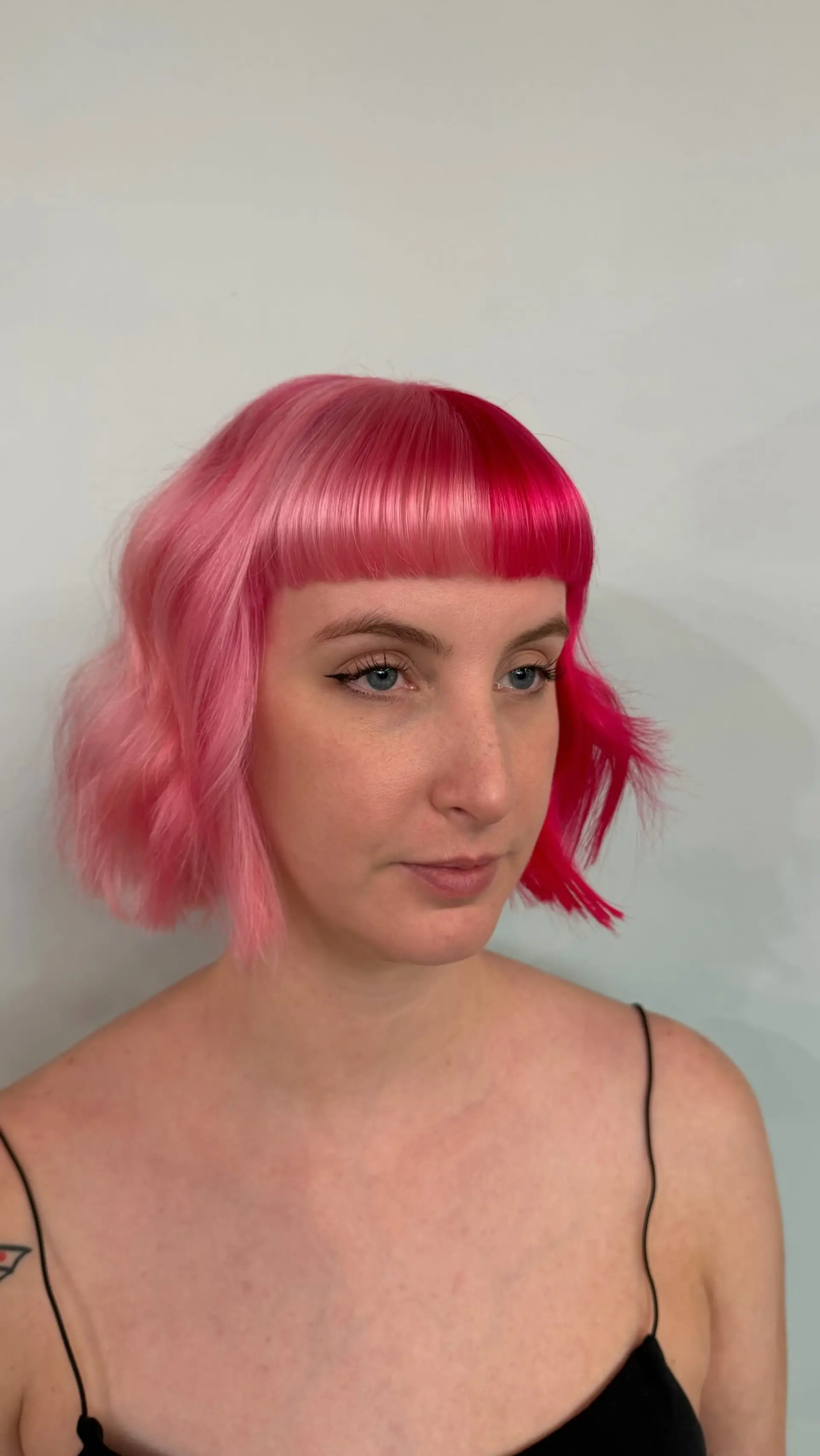 A split-dye chin-length bob pairing soft pastel pink with vibrant hot pink, finished with straight blunt bangs and gentle wave texture. 1