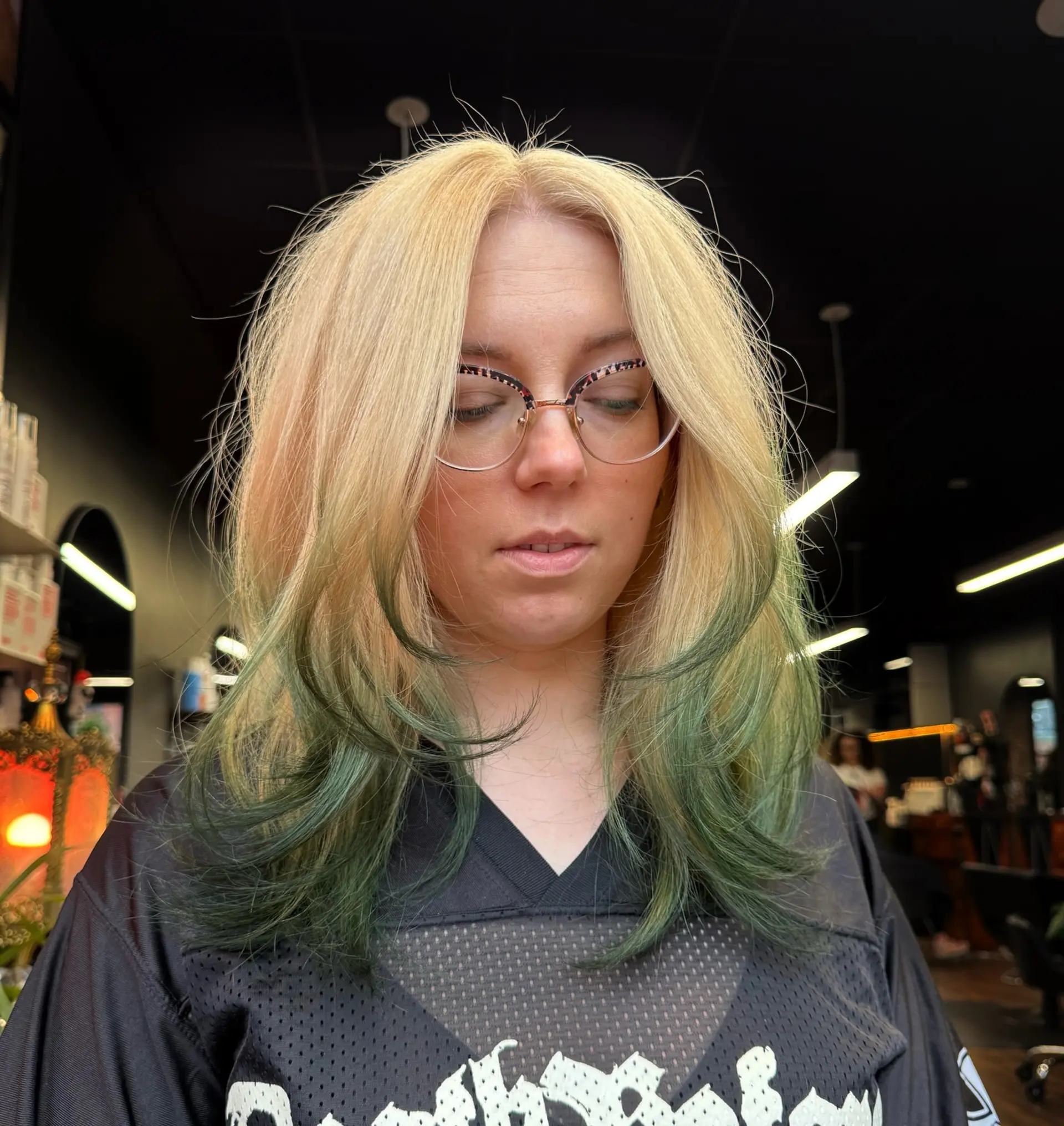 A voluminous, mid-length layered cut featuring pale blonde hair with contrasting forest green dipped ends styled in soft, curved layers. 1