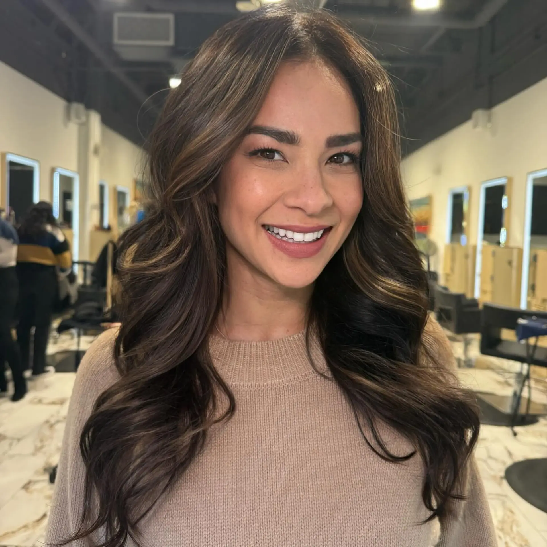 Long, flowing rich brunette hair styled into voluminous, loose soft waves with subtle caramel-toned highlights. 1