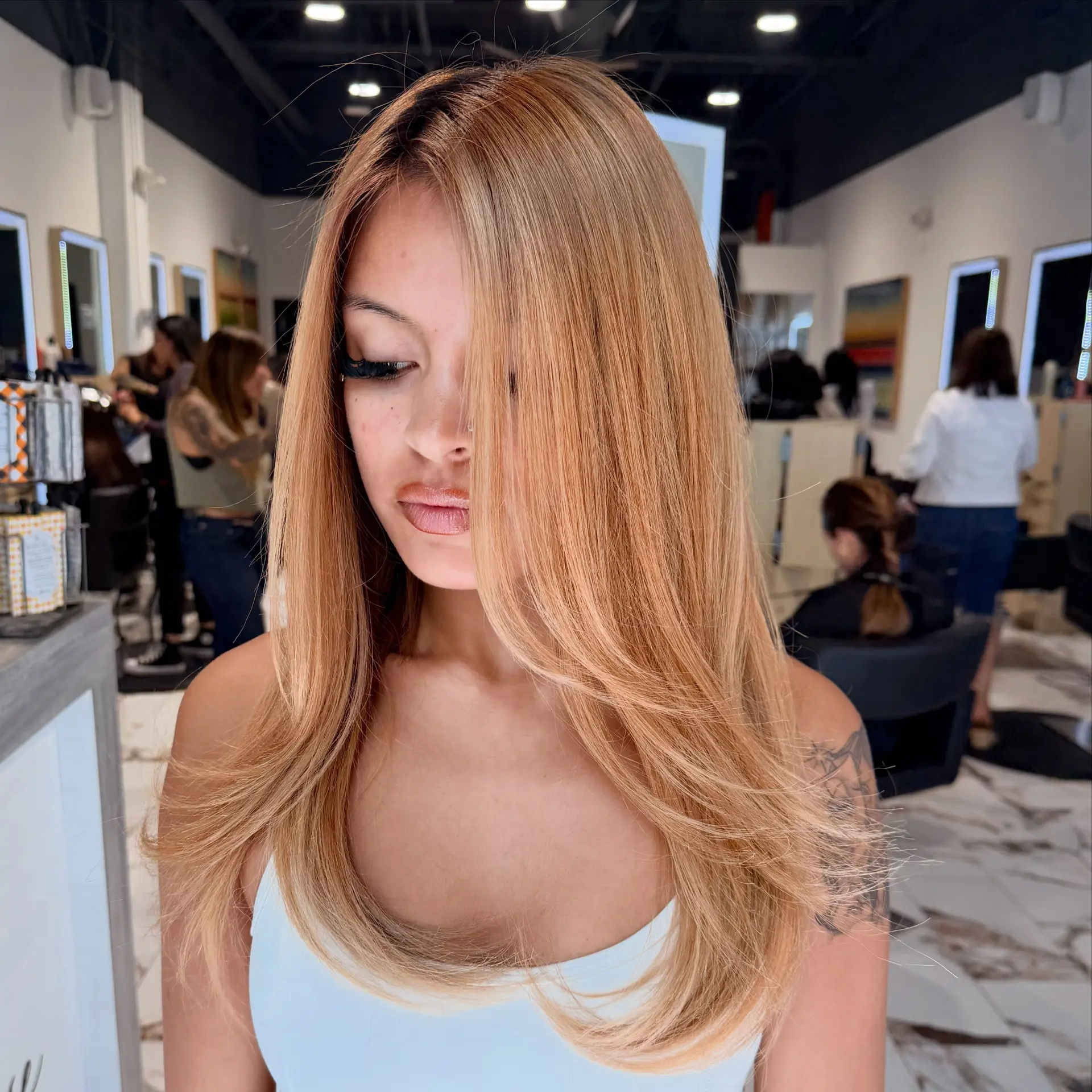 Long honey blonde hair styled smooth and sleek with face-framing layers and soft, rounded ends. 1