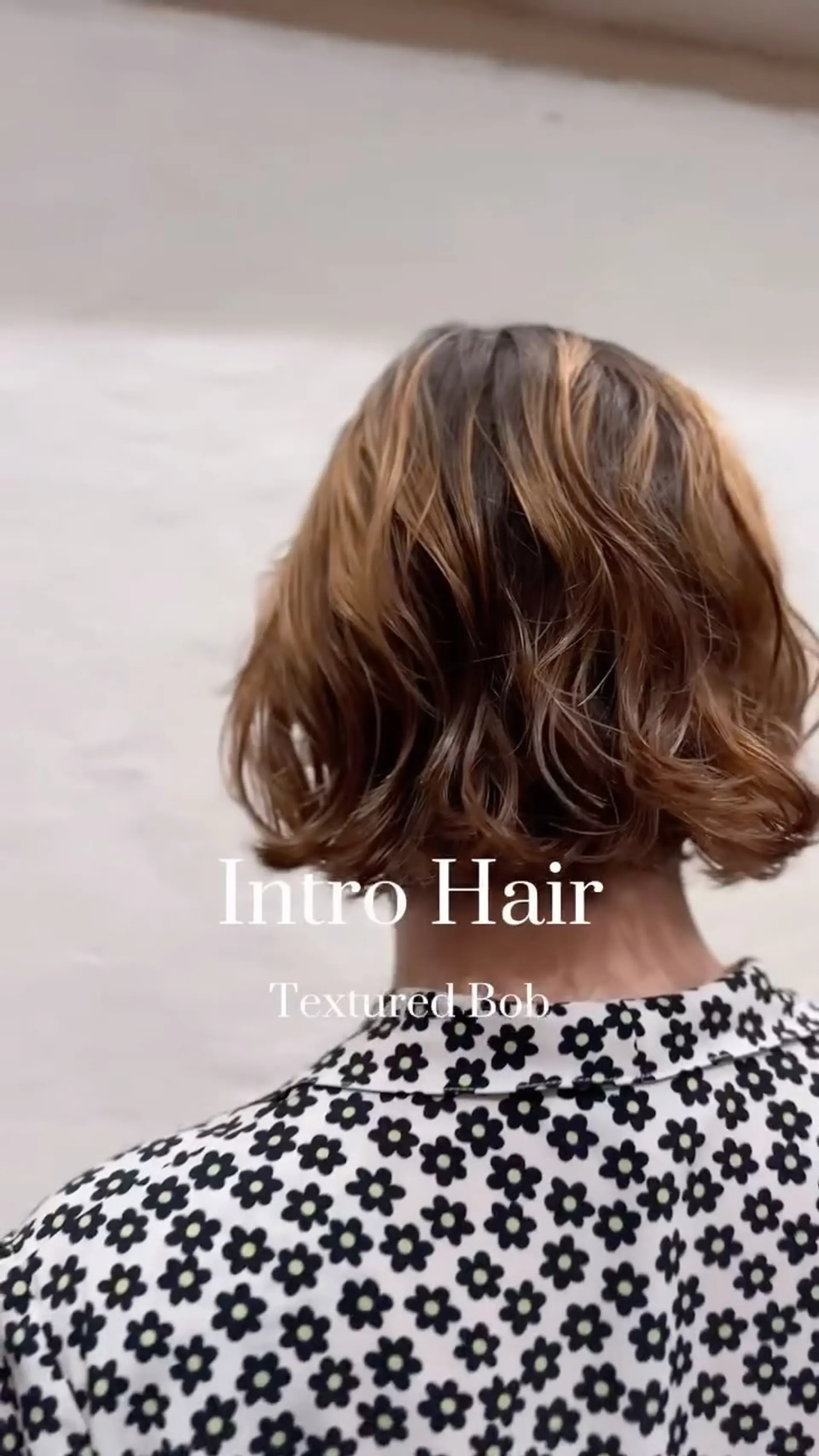 A textured neck-length bob styled with soft, tousled waves and dimensional warm brown tones. 1