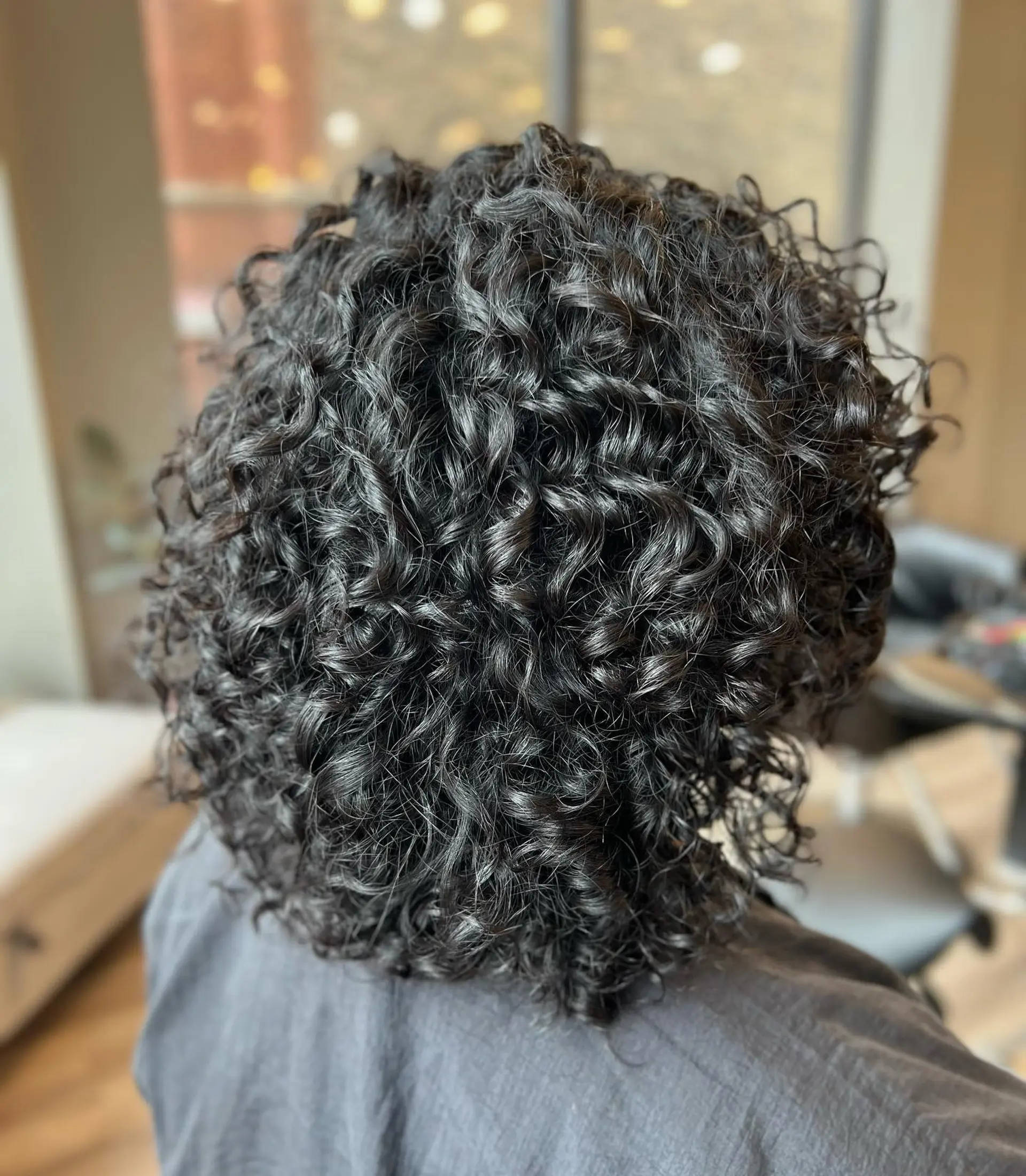 A short, curly hairstyle with natural texture and defined curls. 1