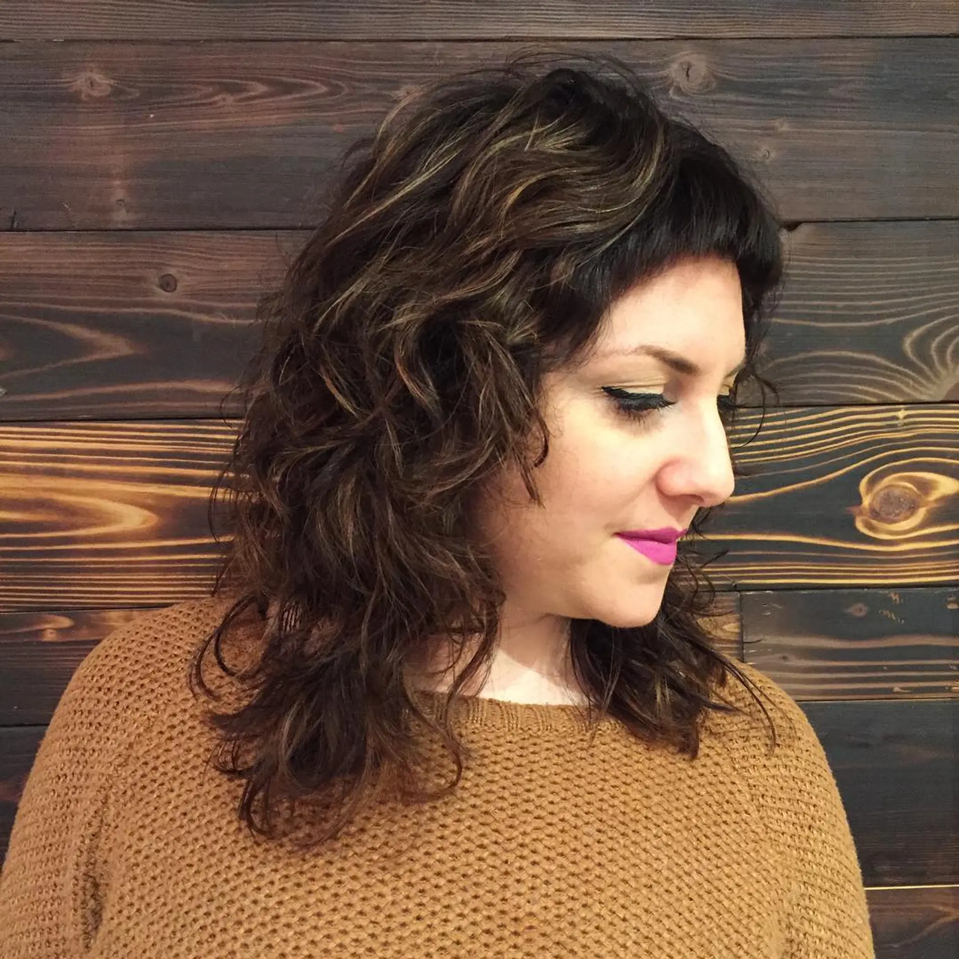 A medium length wavy shag haircut with textured layers and short baby bangs. 1