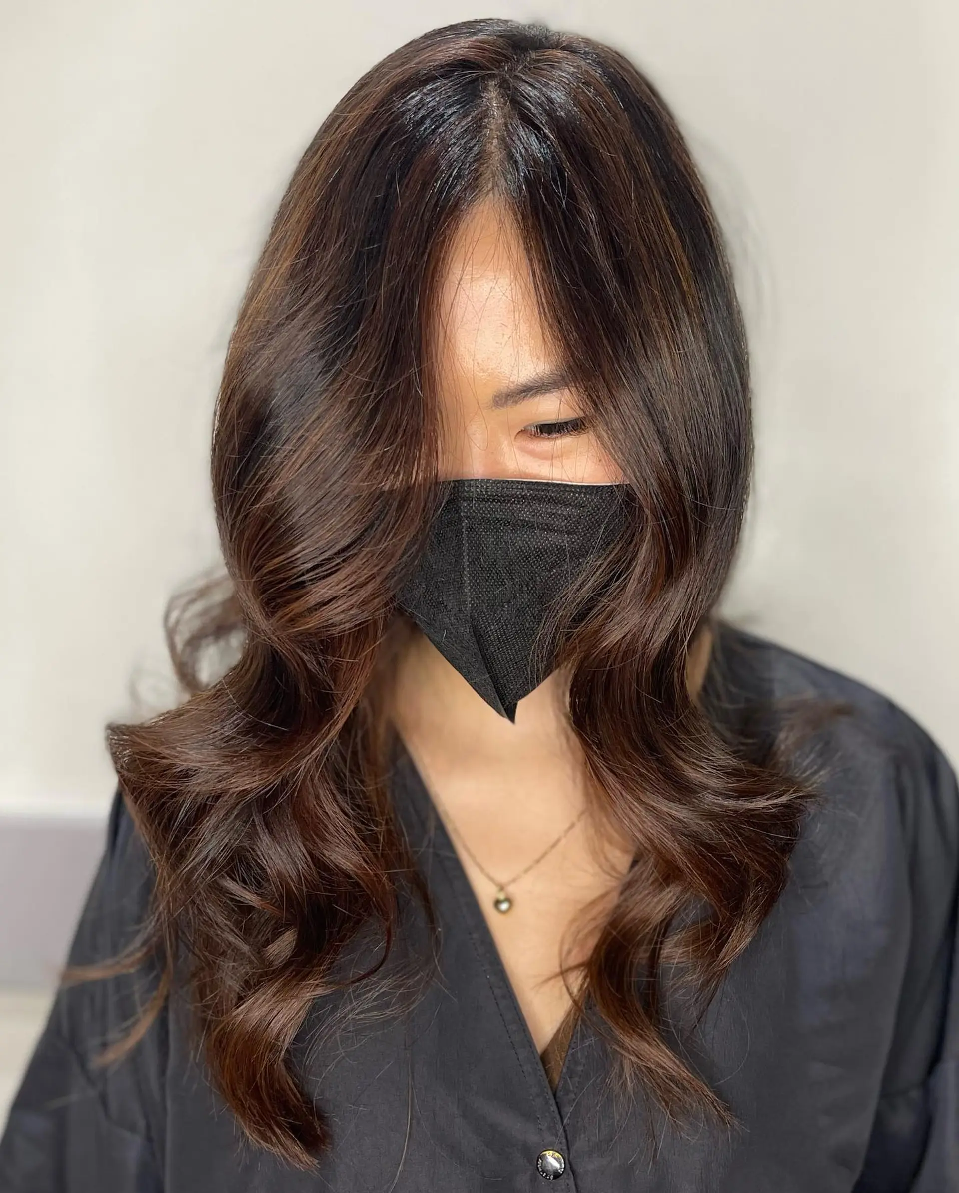Rich, multi-dimensional warm brunette hair featuring soft balayage highlights styled in sweeping face-framing waves. 1
