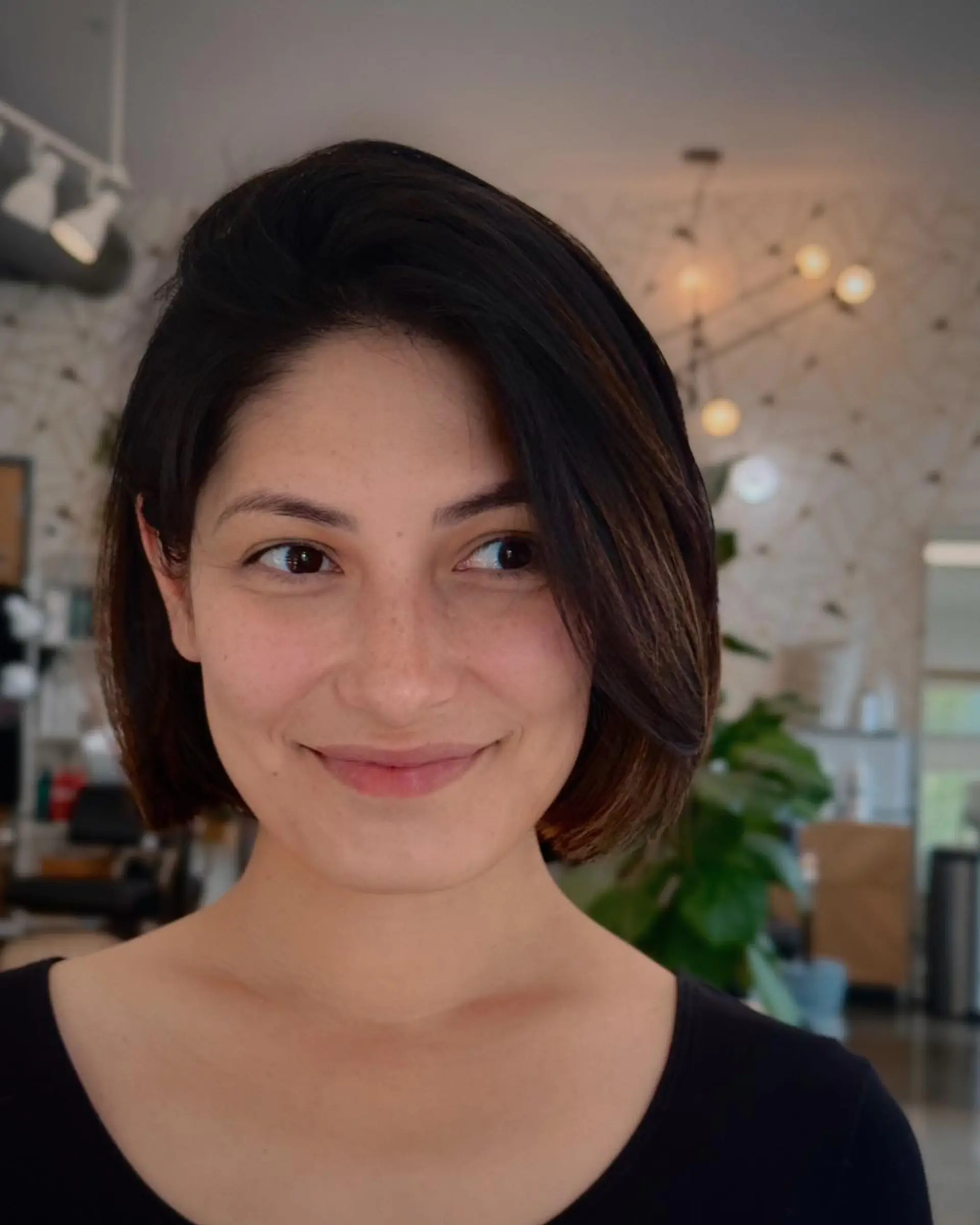A sleek, chin-length bob haircut styled with a deep side part and soft, rounded edges. 1