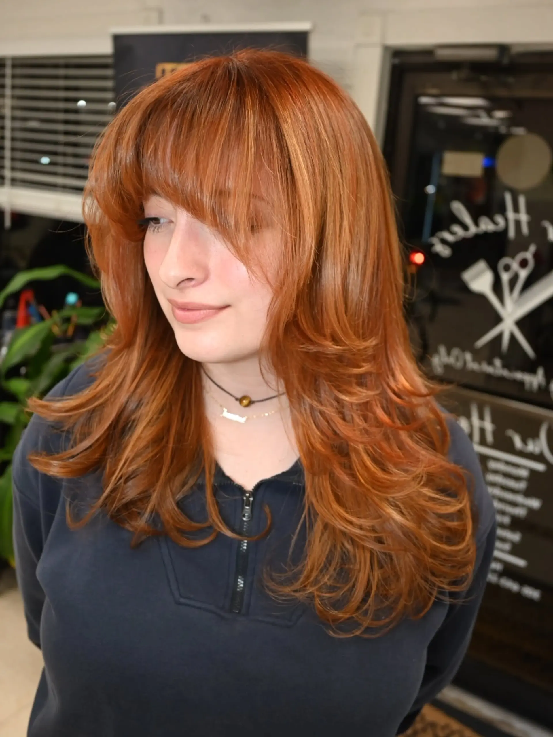 A vibrant copper layered cut with full straight-across bangs and soft face-framing flicks. 1