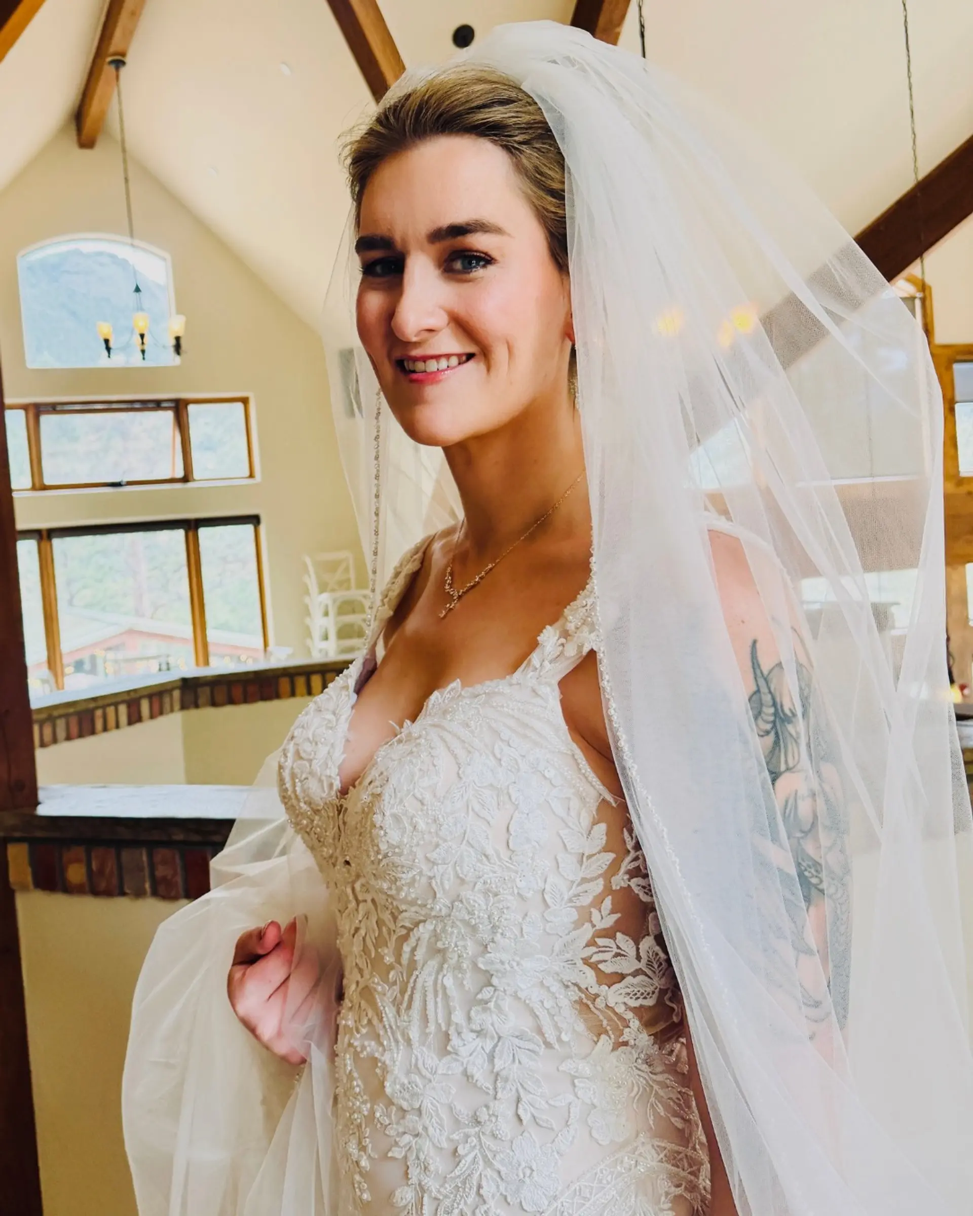 A bridal updo styled neatly away from the face and secured under a dramatic sheer wedding veil. 1