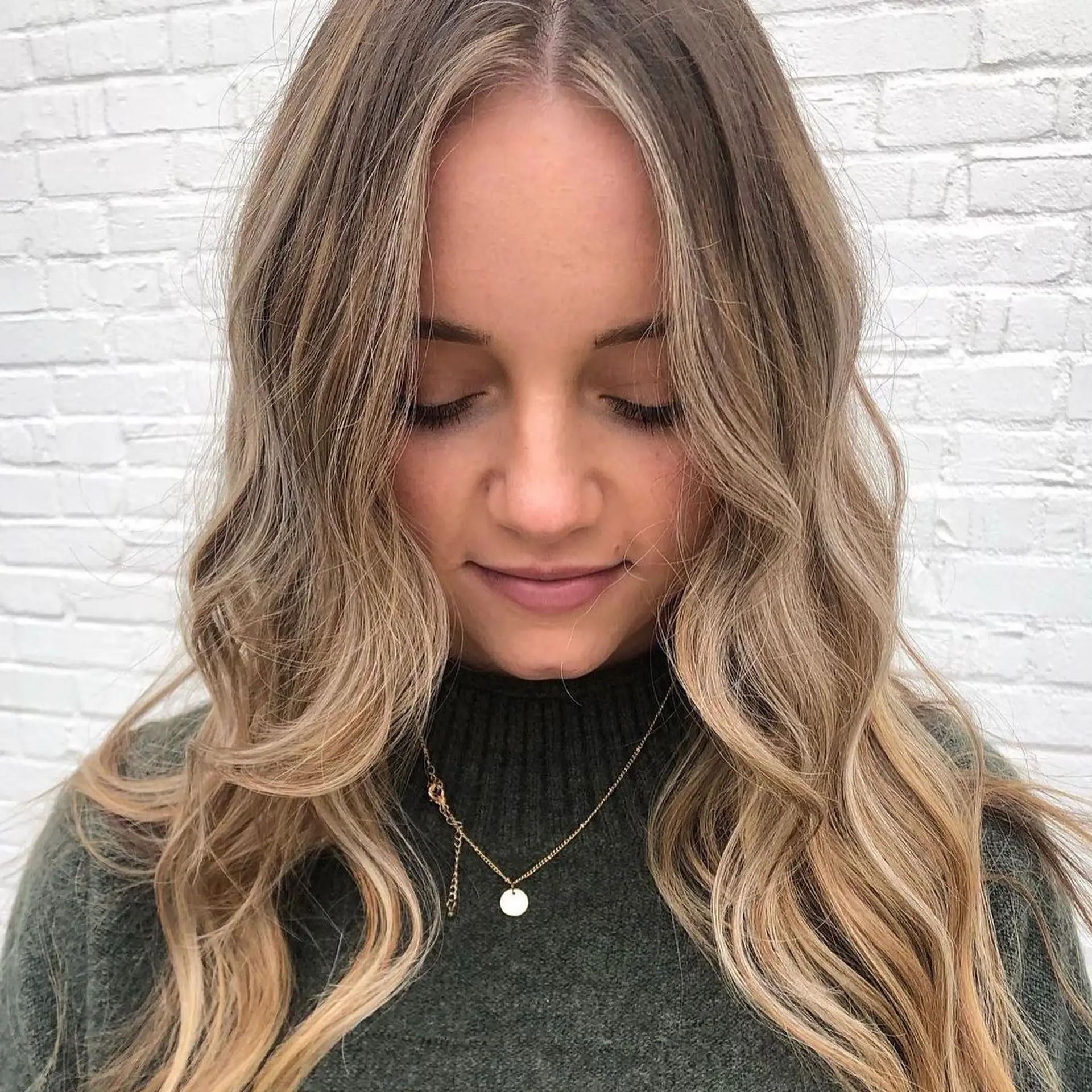 Long dimensional blonde hair parted down the middle and styled with soft, relaxed waves. 1