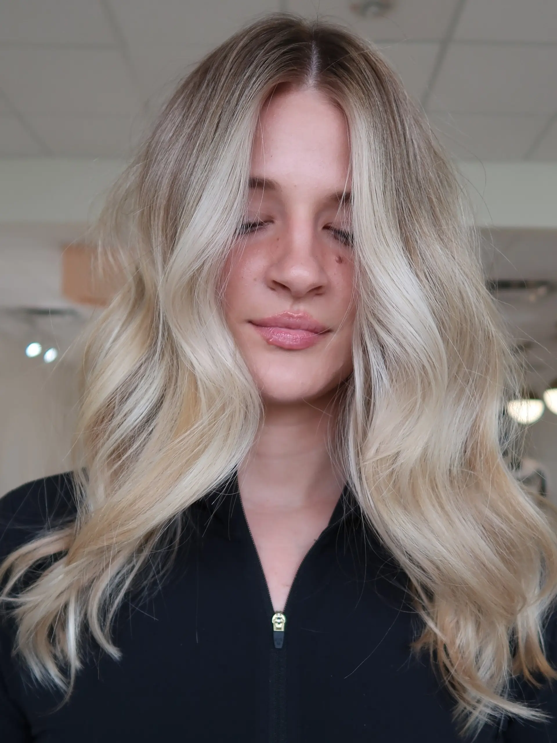 Bright blonde dimensional color styled in loose, voluminous waves with a center part and face-framing money piece highlights. 1