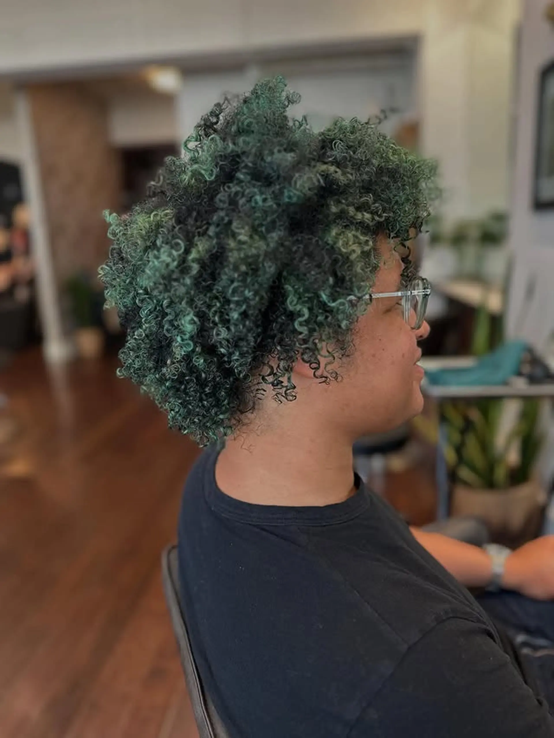 This hairstyle is a vibrant and textured look with defined curls in a seafoam green color. 1