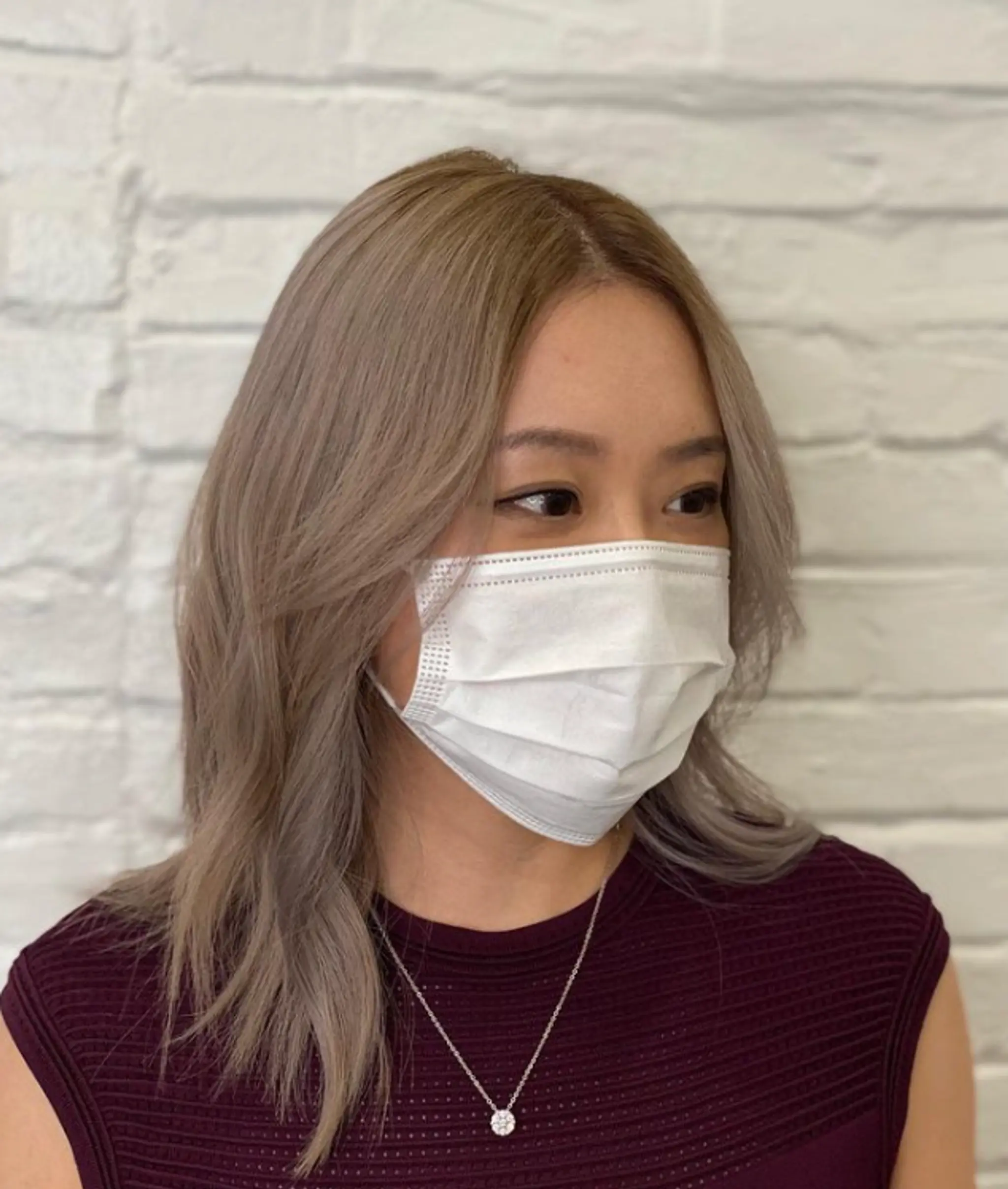 Medium-length, straight with subtle waves, ash blonde and silver color, layered with a side part for a soft and elegant look.