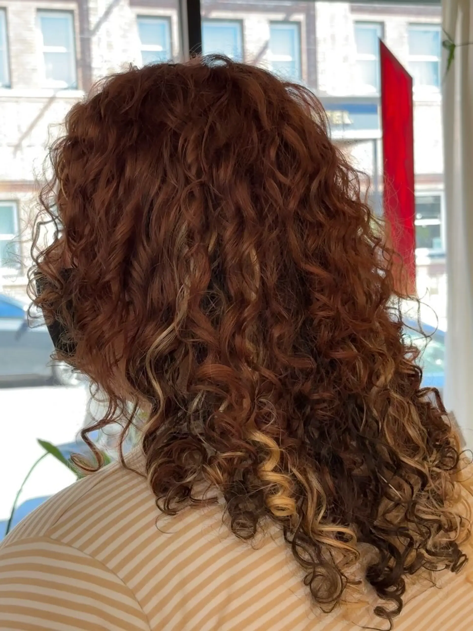 Defined, bouncy curls colored with a warm dimensional mix of auburn, copper, and blonde ribbon highlights. 1