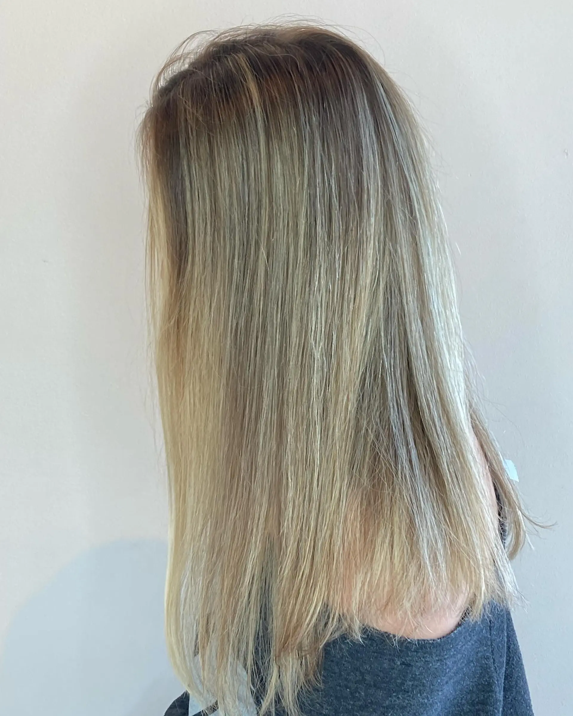 Long, sleek straight hair featuring a lived-in blonde balayage with natural darker roots transitioning into bright ash and golden blonde tones. 1