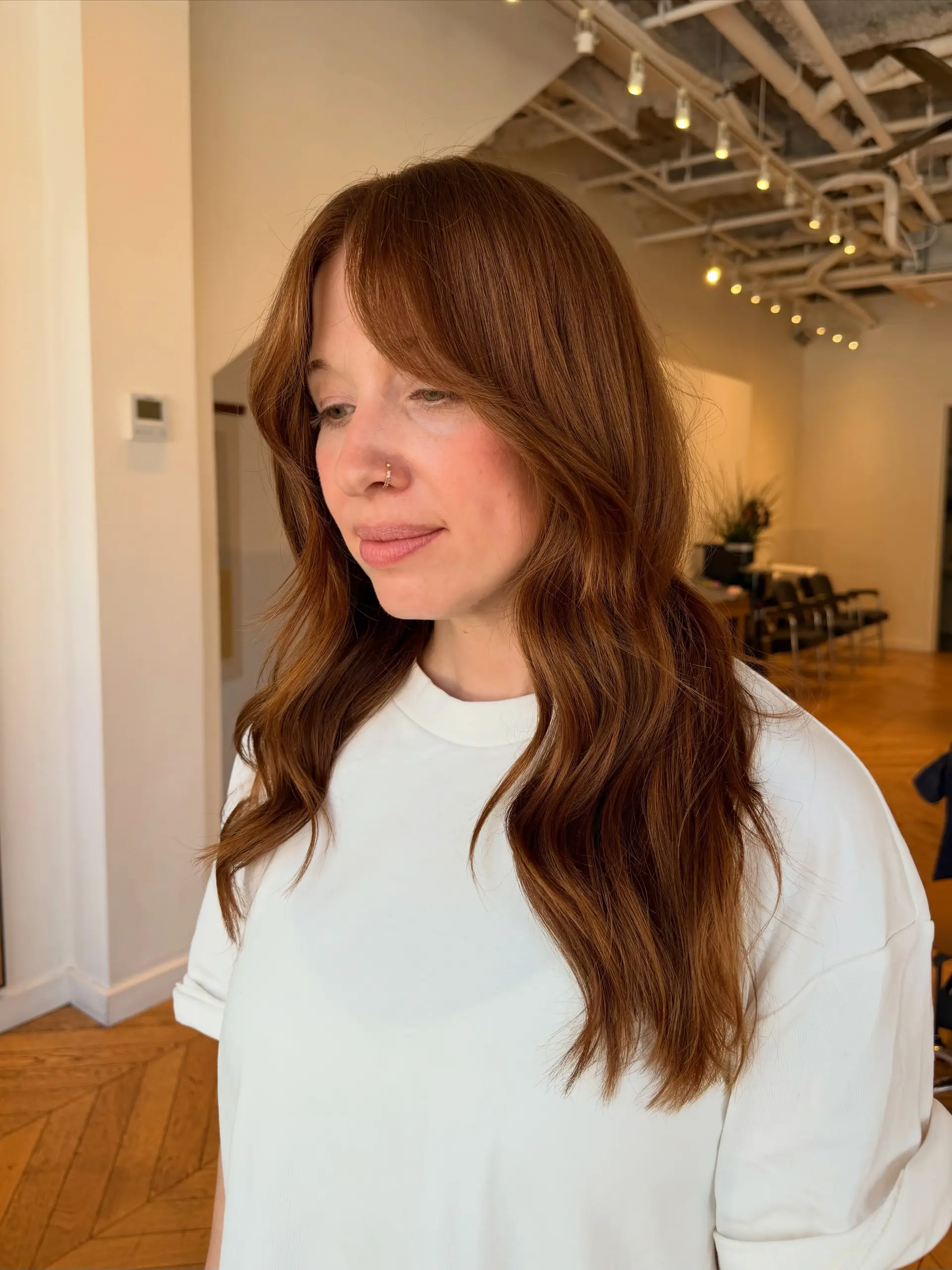 Long auburn hair featuring soft waves, gentle layers, and face-framing curtain bangs. 1