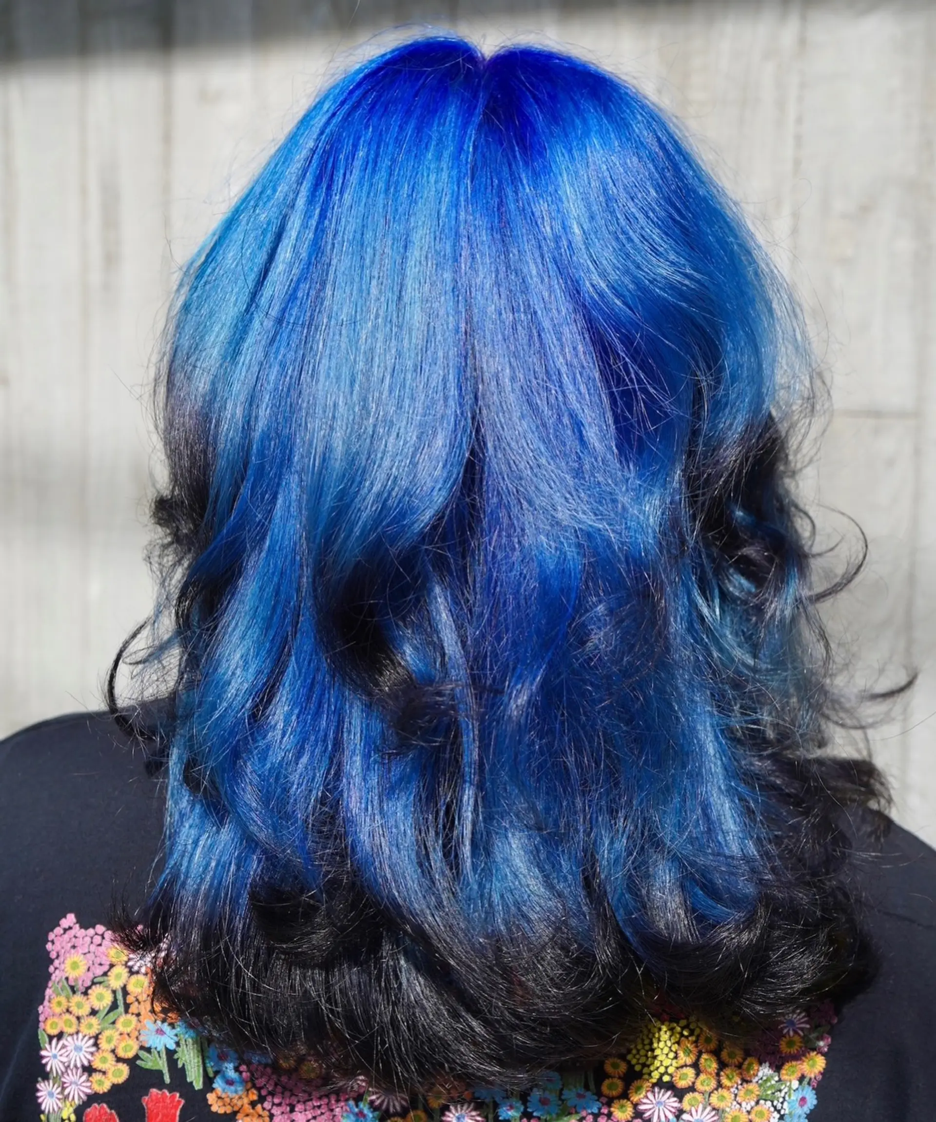 Vivid electric blue hair styled in loose waves with dark black lowlights underneath. 1