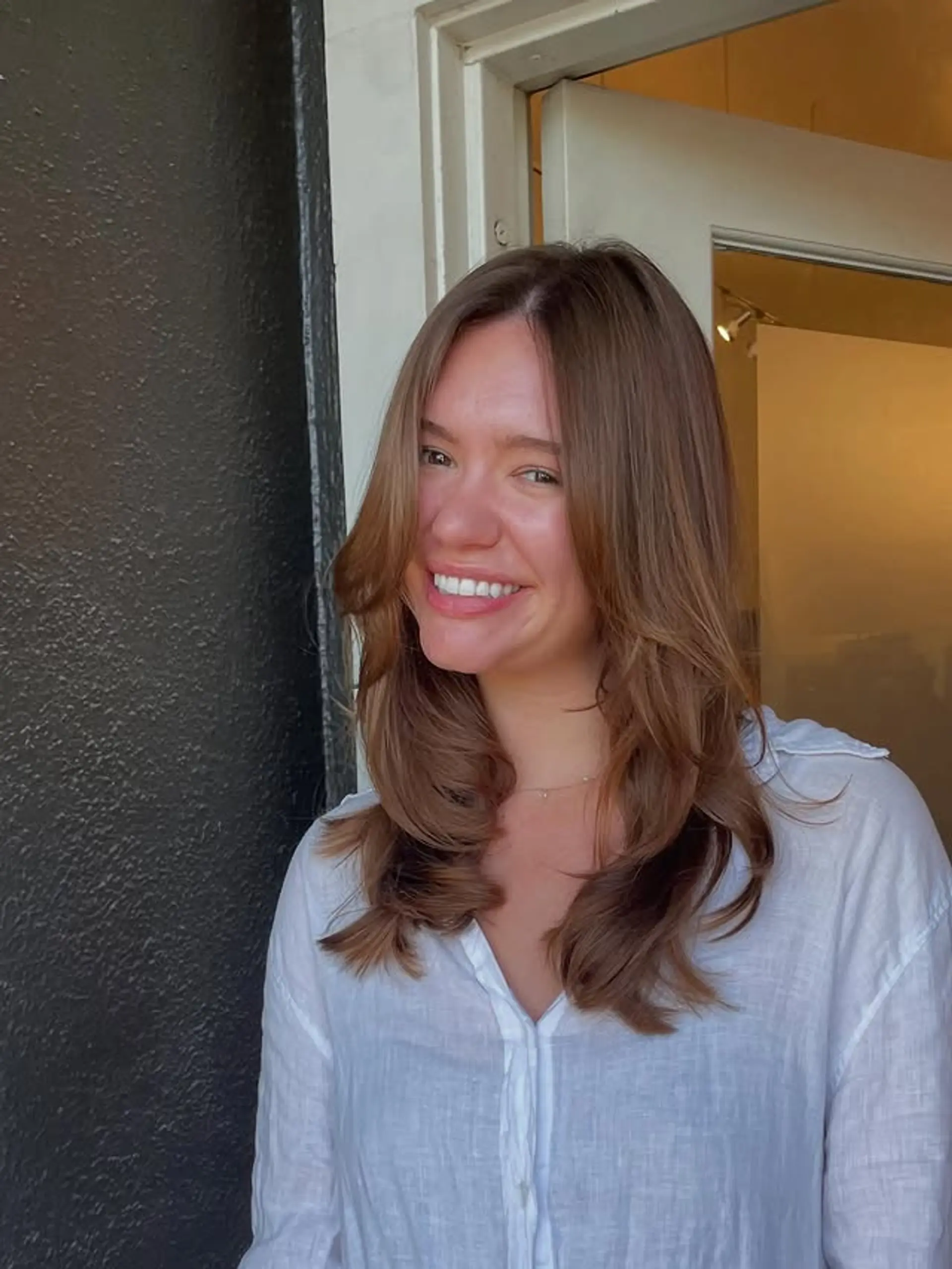 A medium-length layered haircut with flattering curtain bangs and face-framing layers. 1