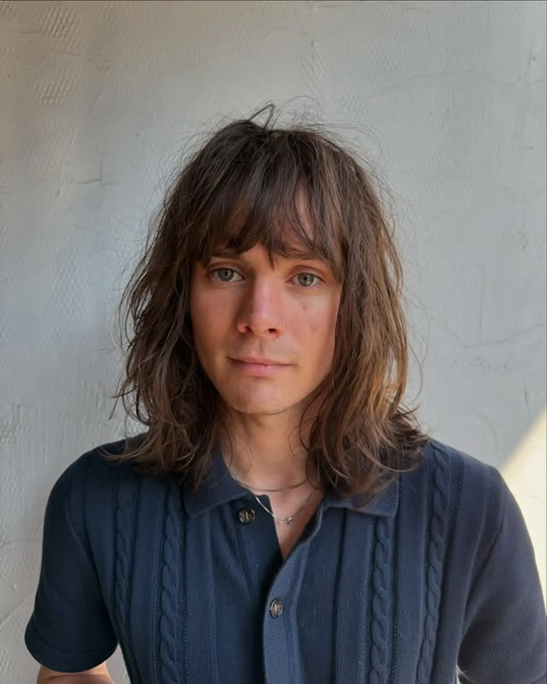 A 70s-inspired long wavy hairstyle with blunt bangs and layered cut. 1