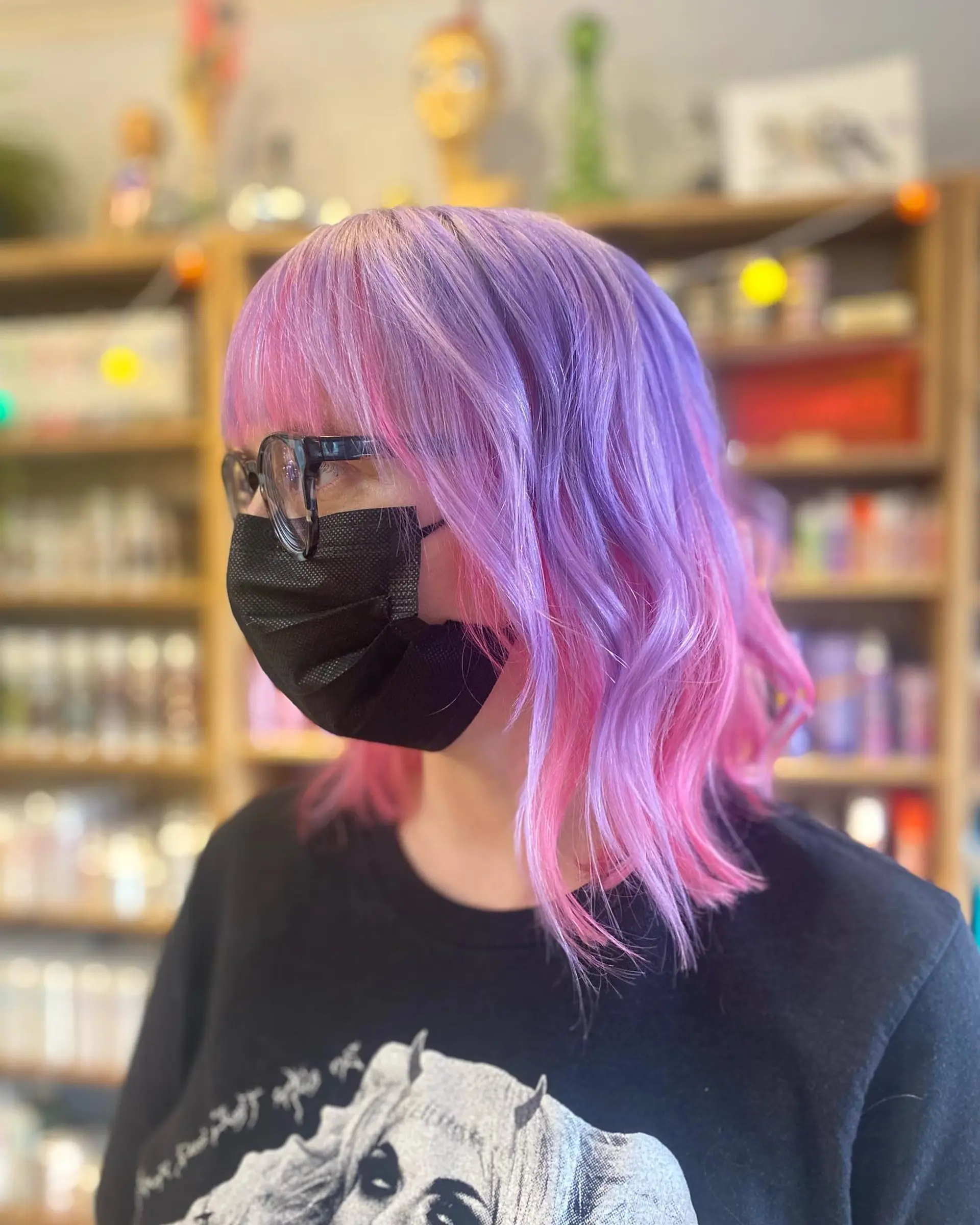 A vibrant medium-length hairstyle featuring a stunning blend of pink and purple pastel colors, styled with subtle waves and fringe bangs. 1