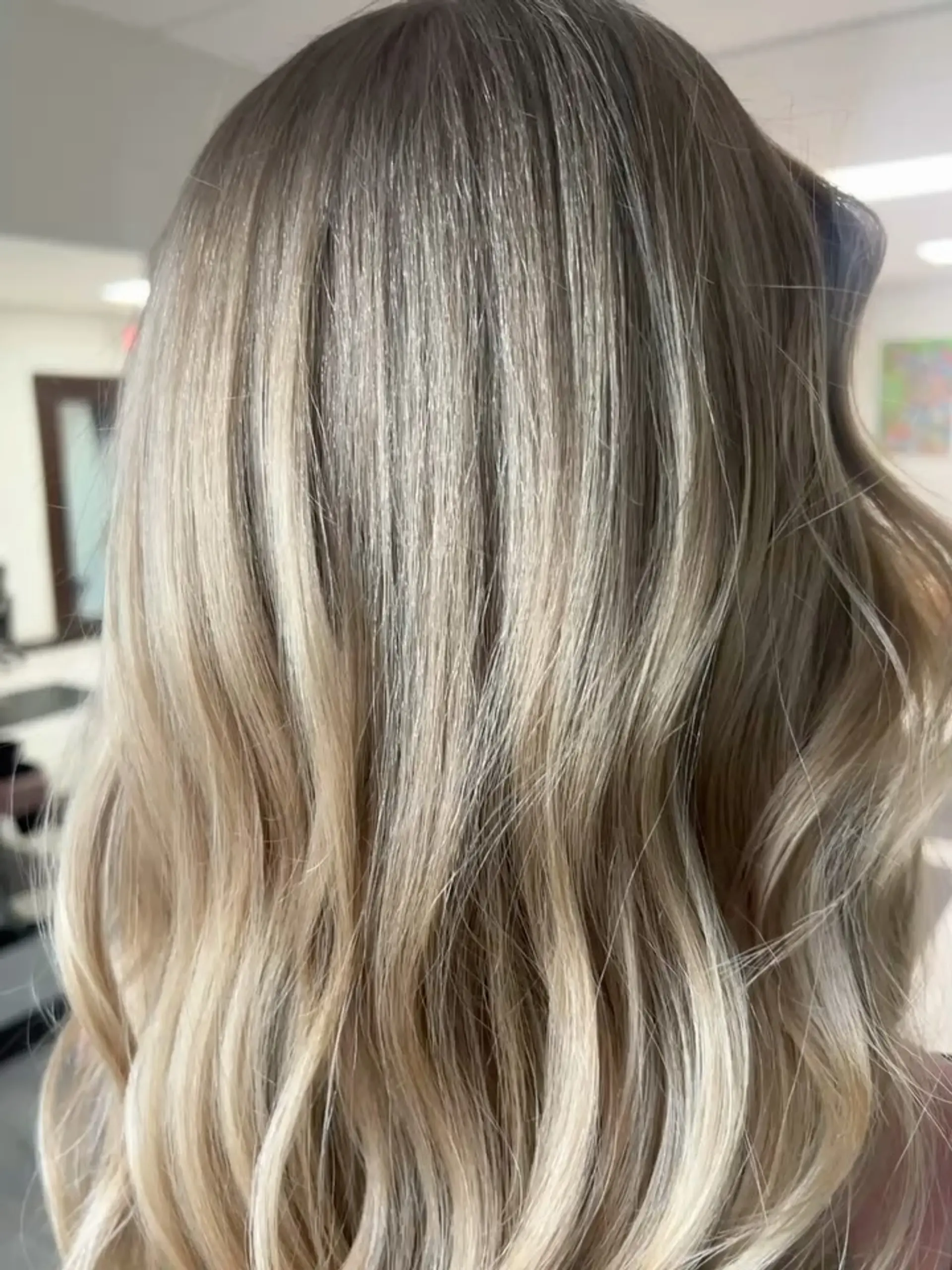 Long blonde hair cut with prominent layers and styled into soft, flowing waves. 1