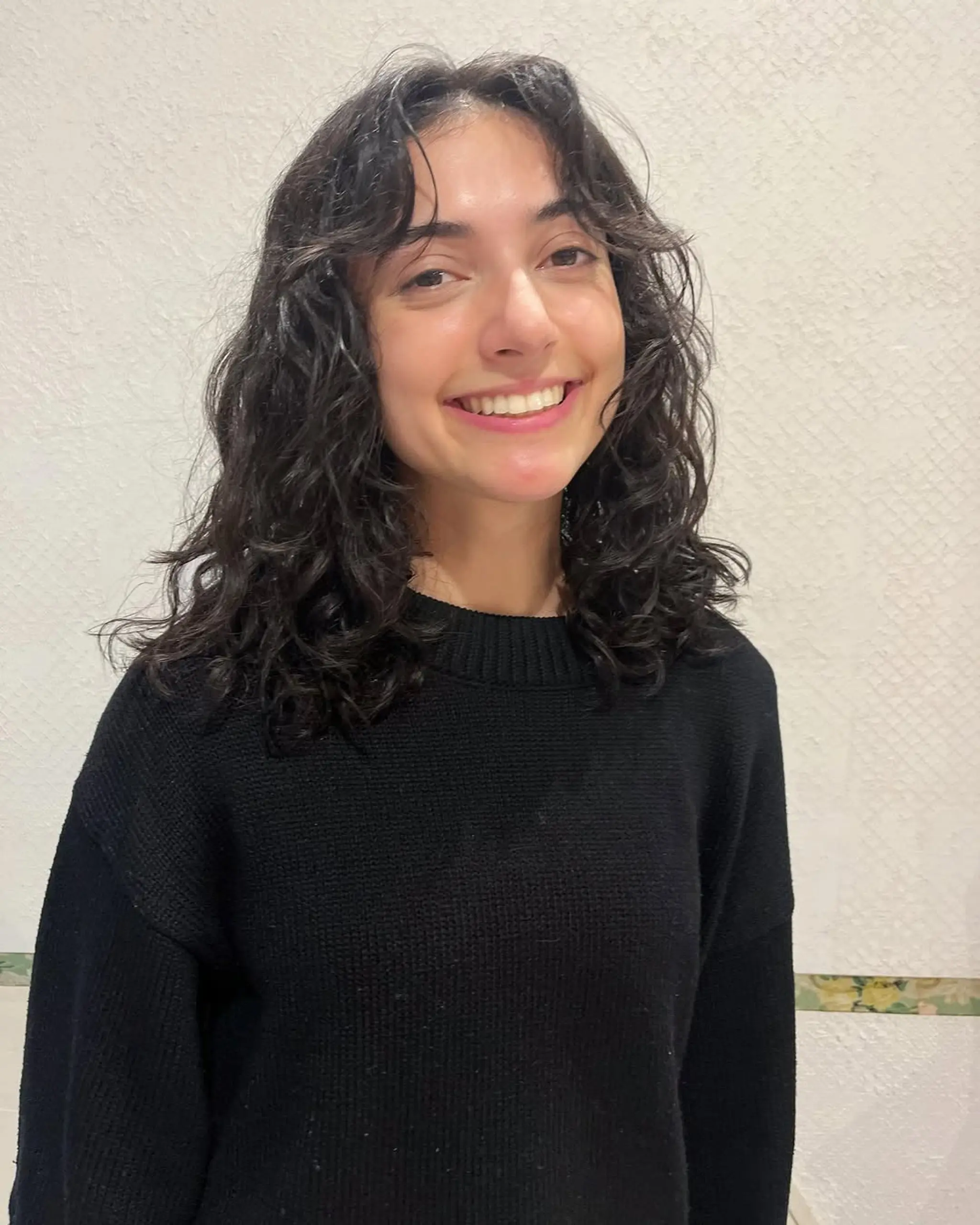 Medium length, dark brown hair with natural, curly cascades and face-framing layers.