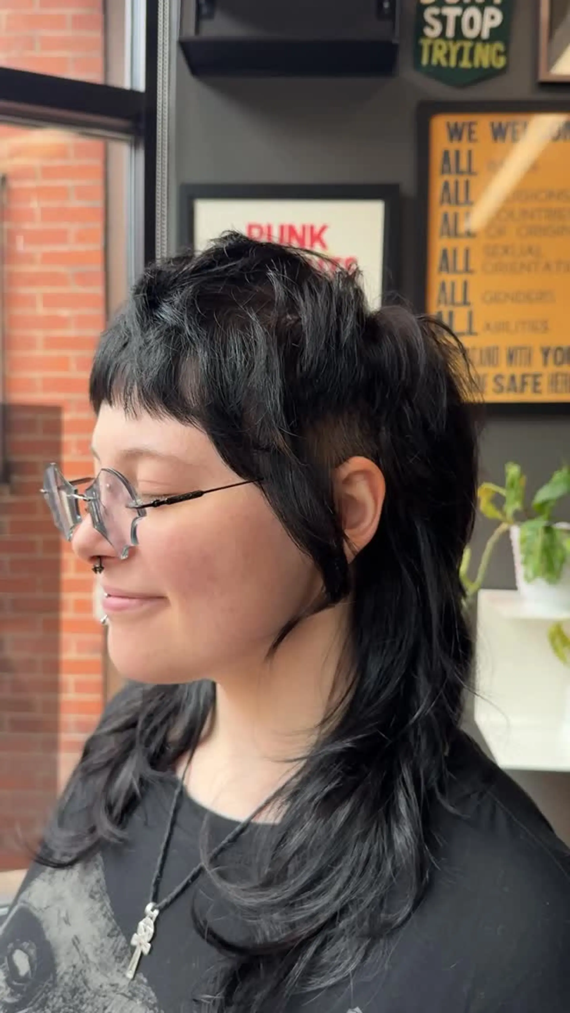 A dark alternative mullet with choppy micro bangs, undercut sides, and feathered layers flowing into mid-length ends. 1