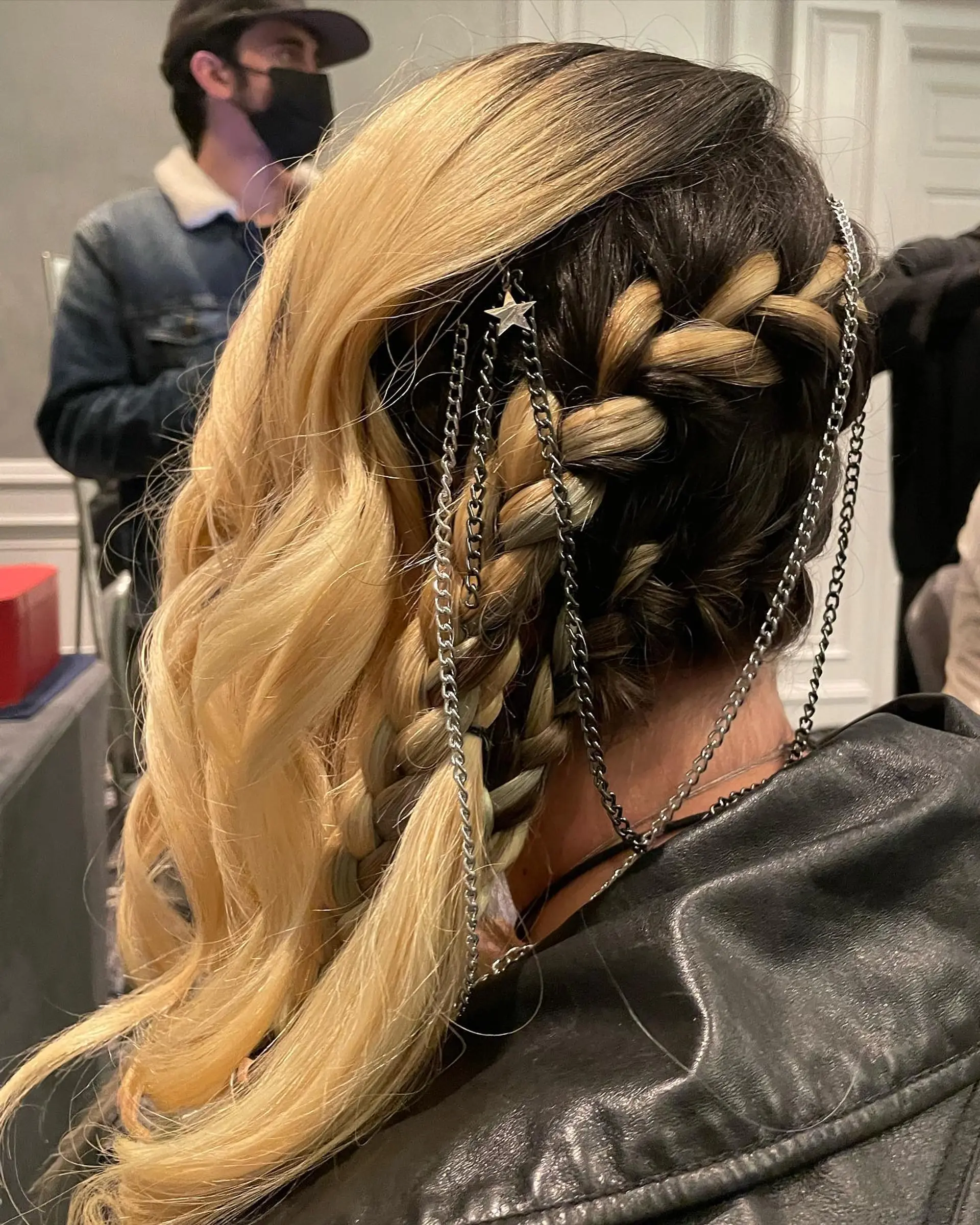 A creative, edgy side-swept style combining dimensional braids laced with silver chains and star accessories alongside soft blonde waves. 1