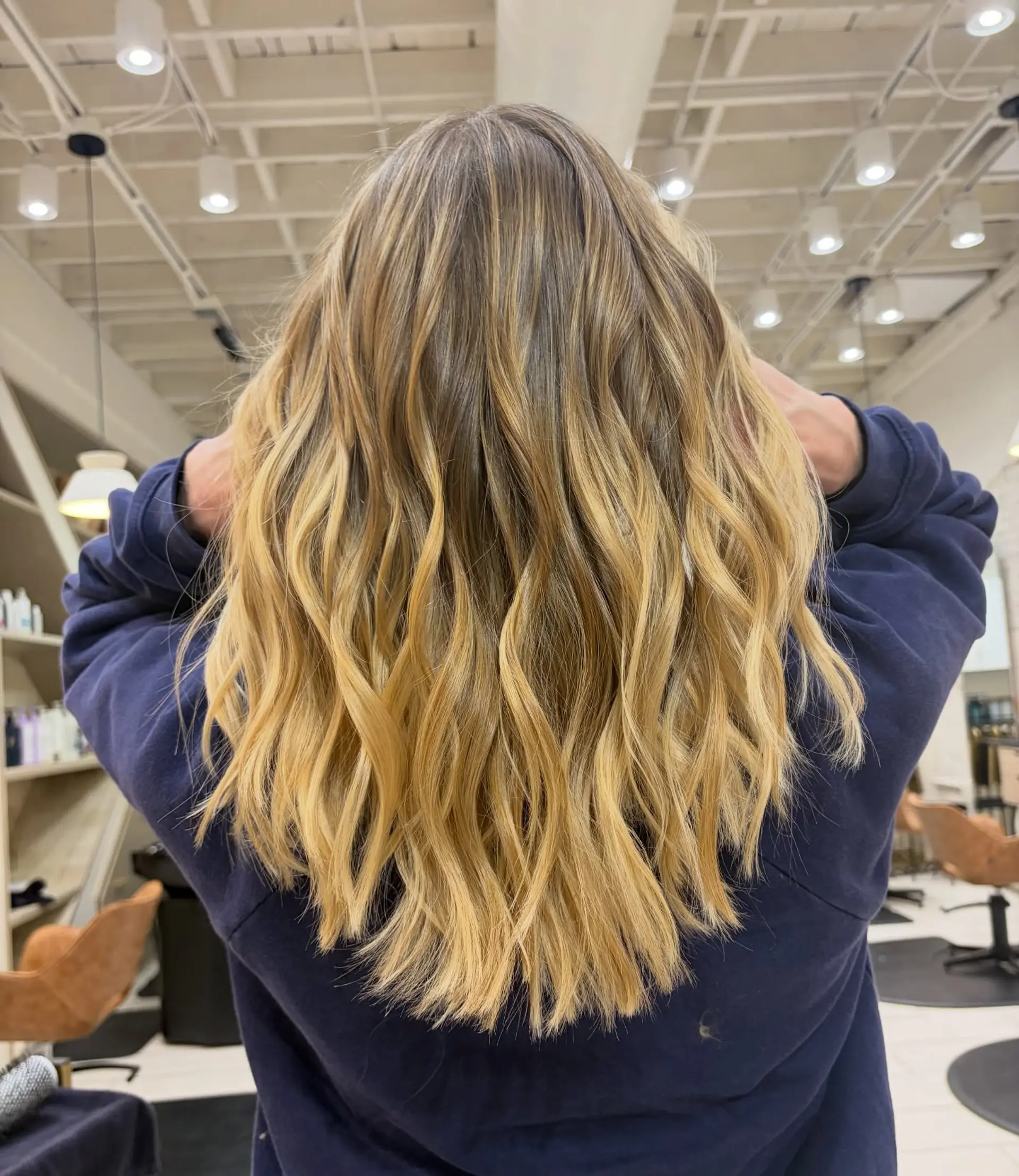 Long hair featuring a seamless lived-in blonde balayage styled with textured, beachy waves. 1
