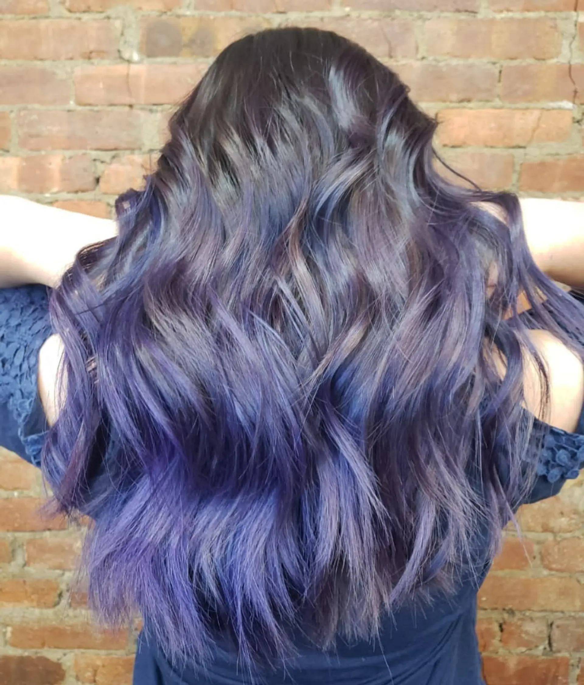 Long wavy hair with a dark base blending smoothly into vibrant violet and blue balayage highlights. 1