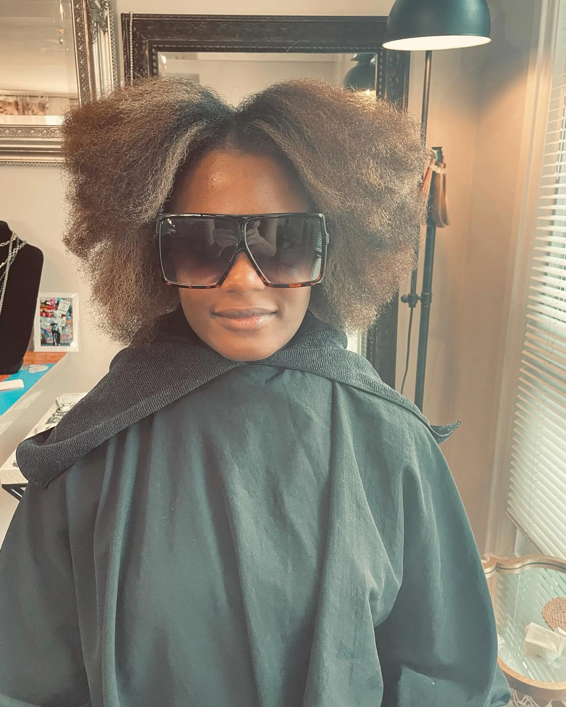 Voluminous blown-out natural hair styled with a center part and multidimensional root-shadowed highlights. 1