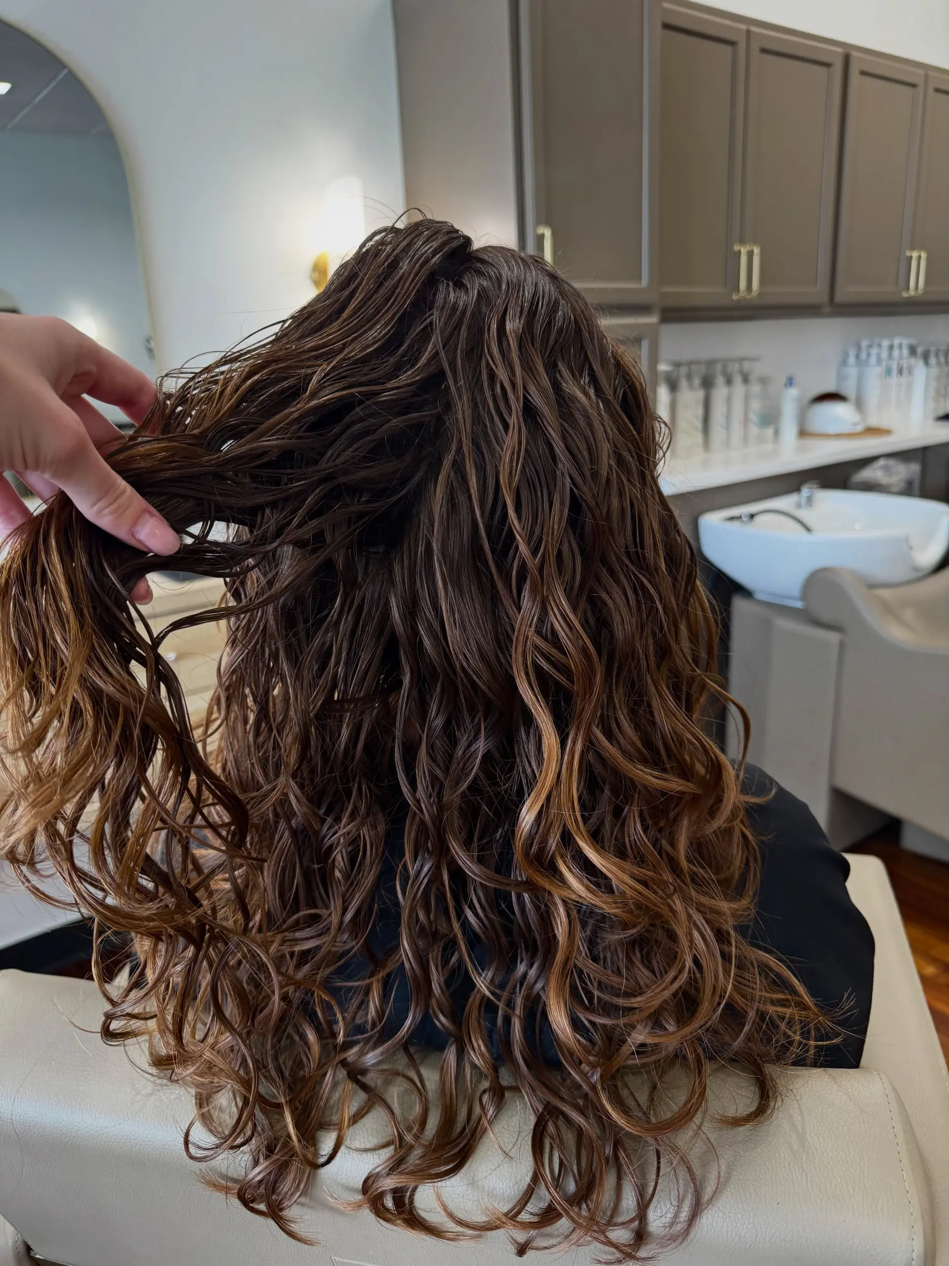 Long brown hair enhanced with curl-defining products, showcasing defined spiral waves and curls from root to tip. 1