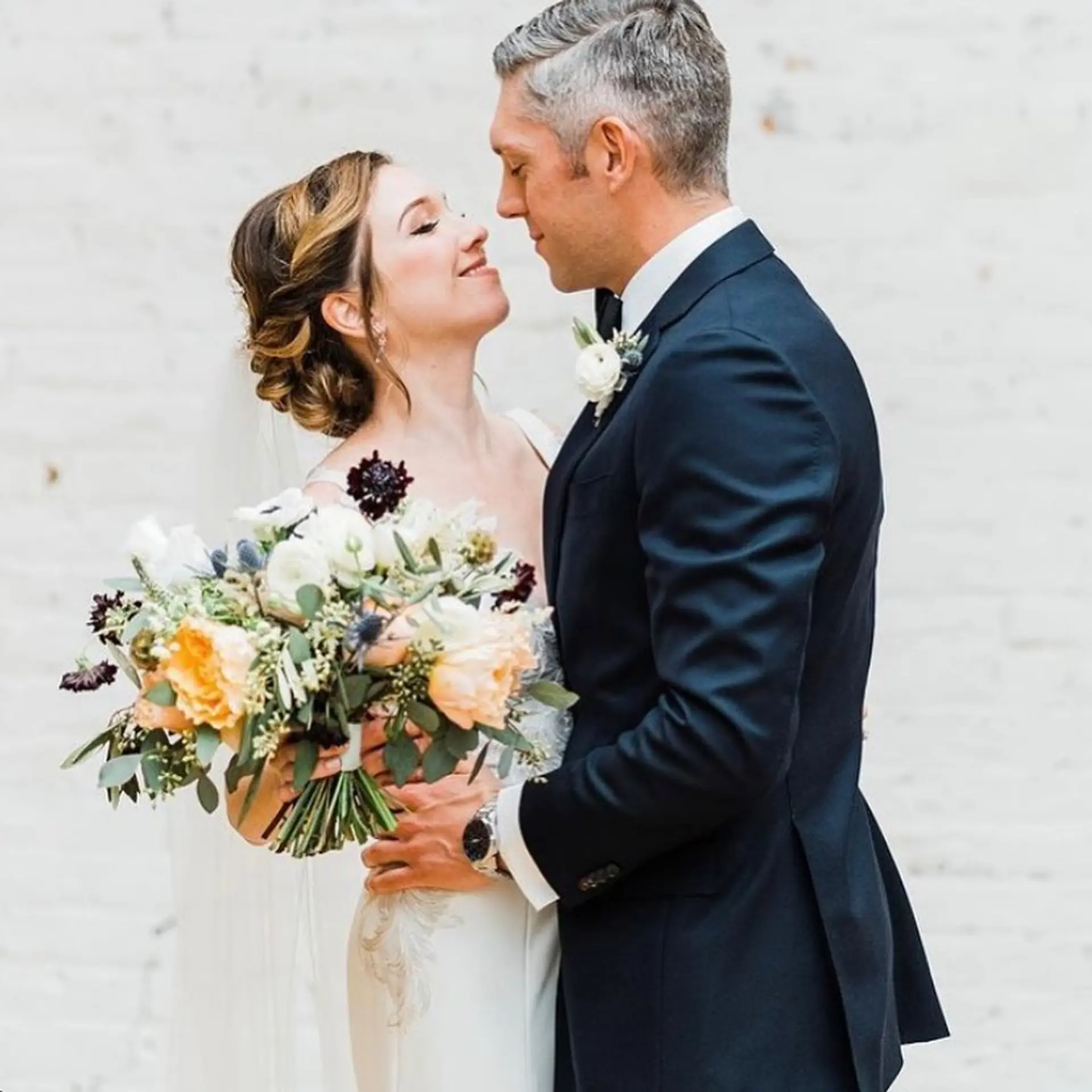 A romantic bridal updo gathered into a textured low bun with soft dimension and swept sides. 1