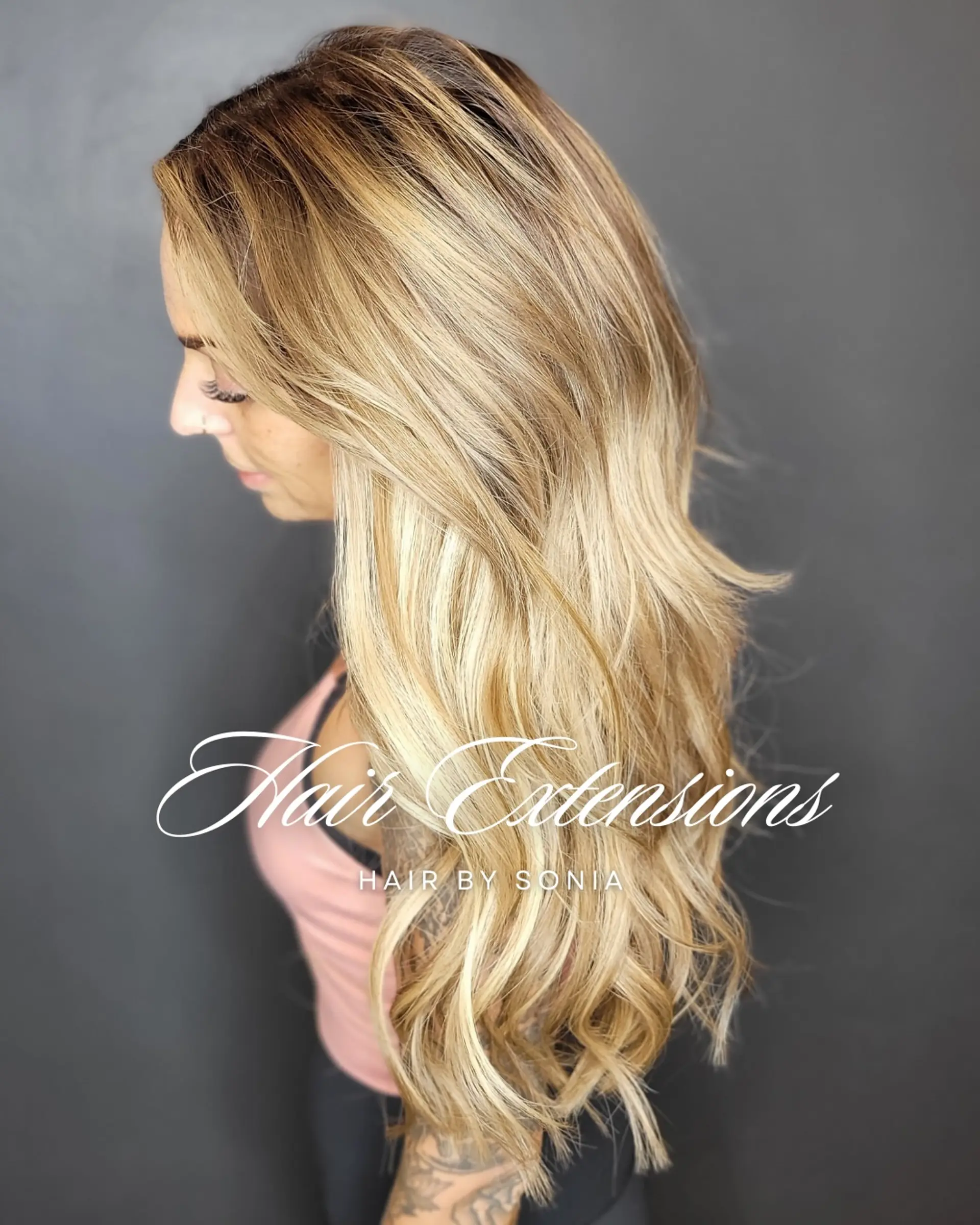 Long, dimensional blonde hair extensions styled in soft, cascading waves. 1