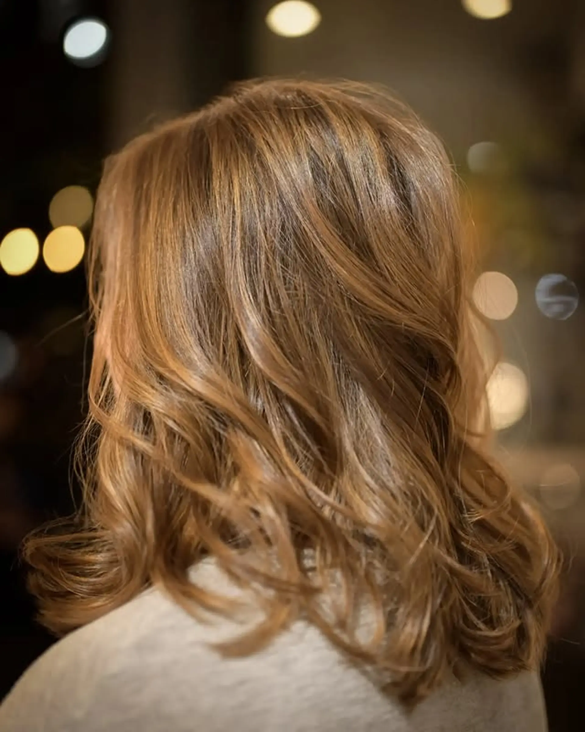 A medium-length wavy hairstyle with a bronde balayage and soft layers. 1