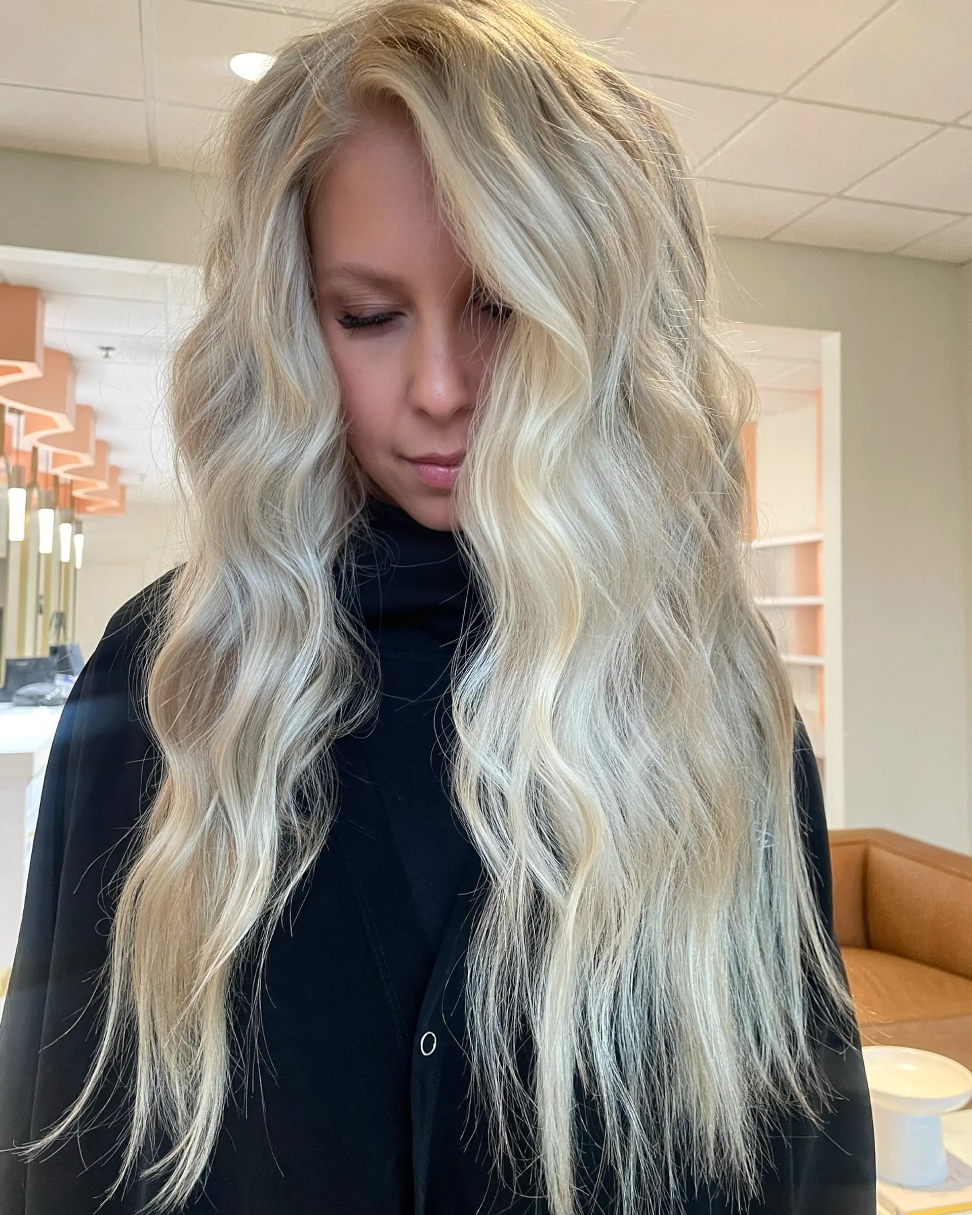 Extra-long platinum blonde hair styled with soft, voluminous beach waves parted slightly off-center. 1