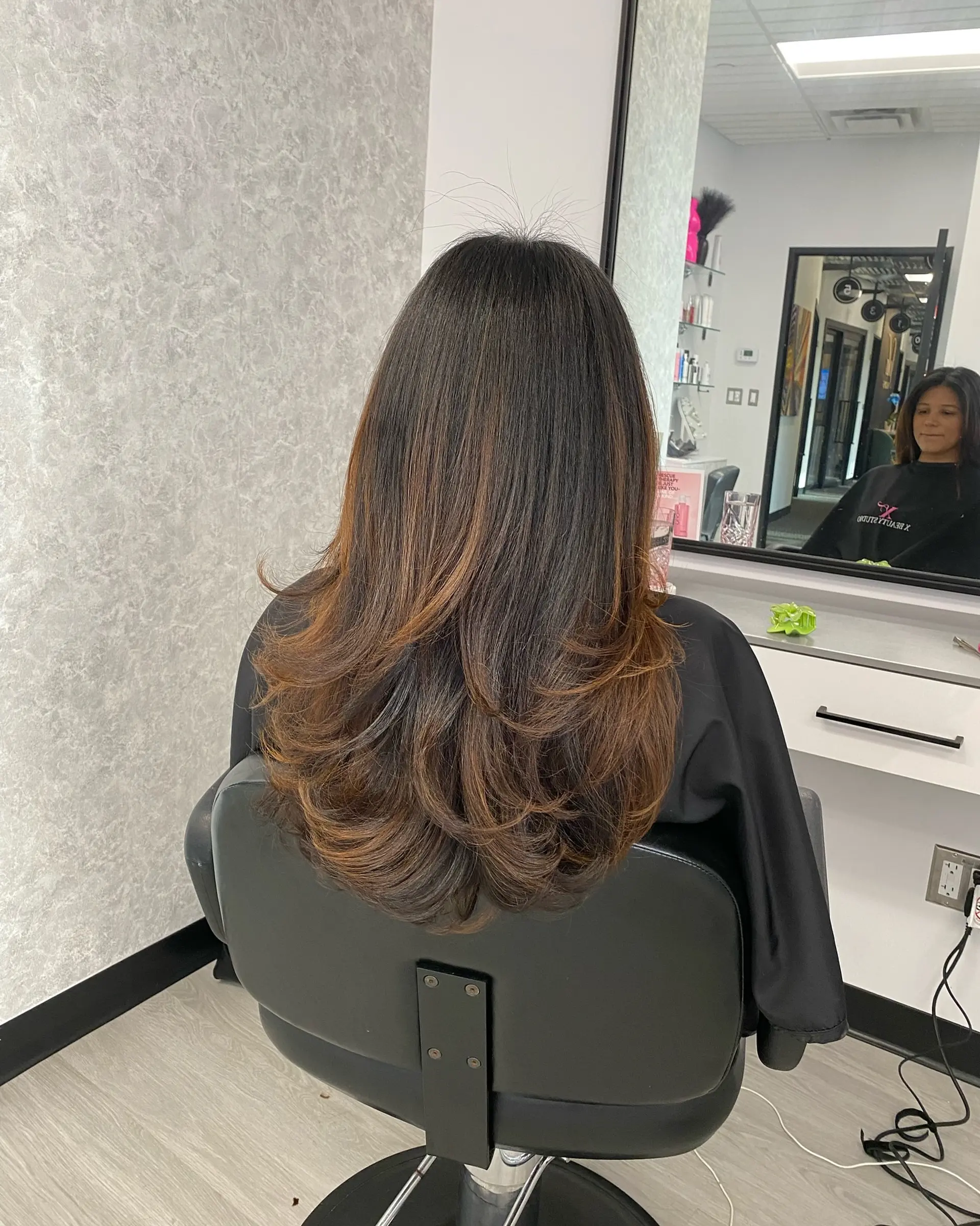 Long dark brown hair featuring flowing layers, warm caramel balayage highlights, and a voluminous blowout with flipped ends. 1