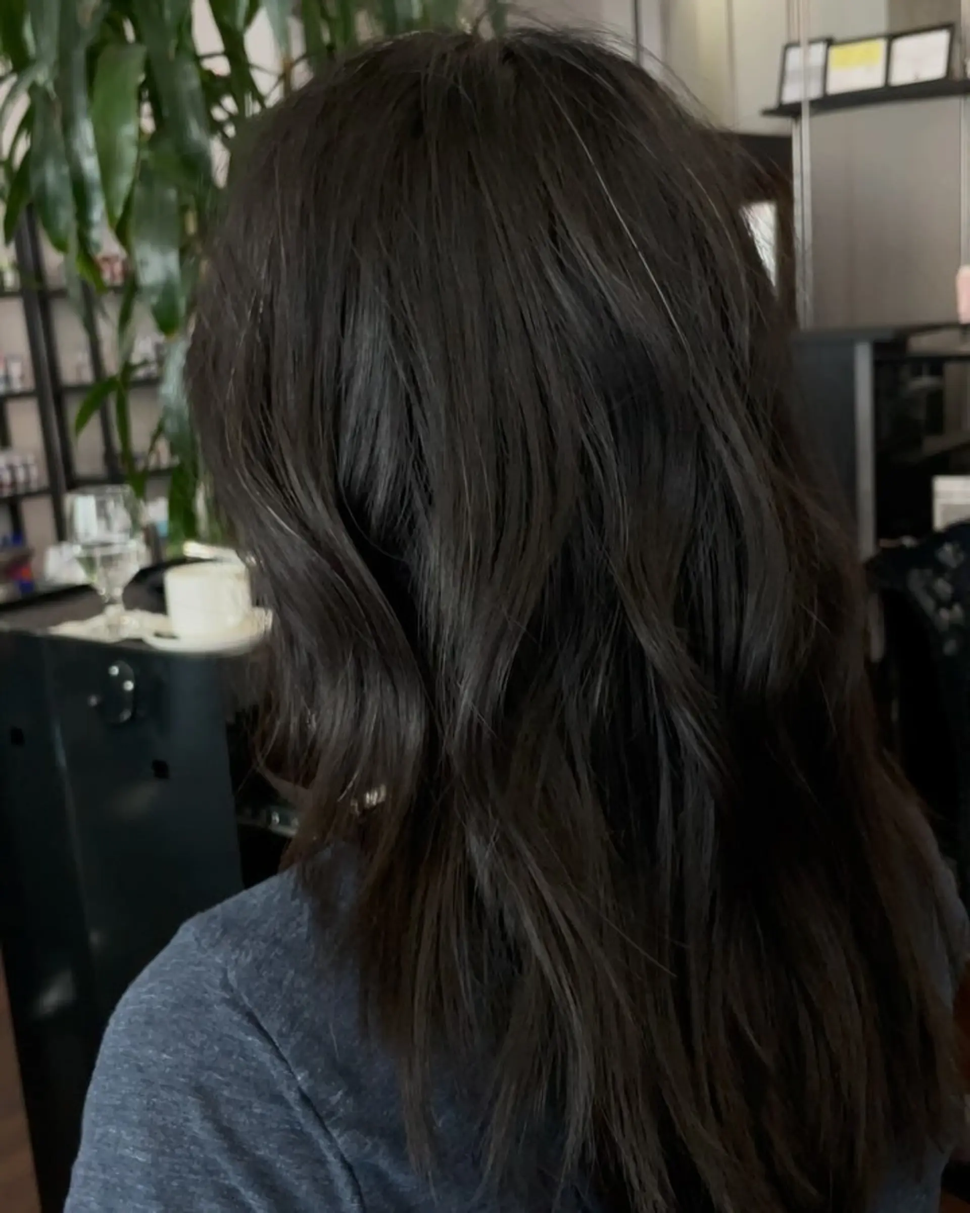 A textured long haircut featuring subtle movement and soft layers on dark hair. 1
