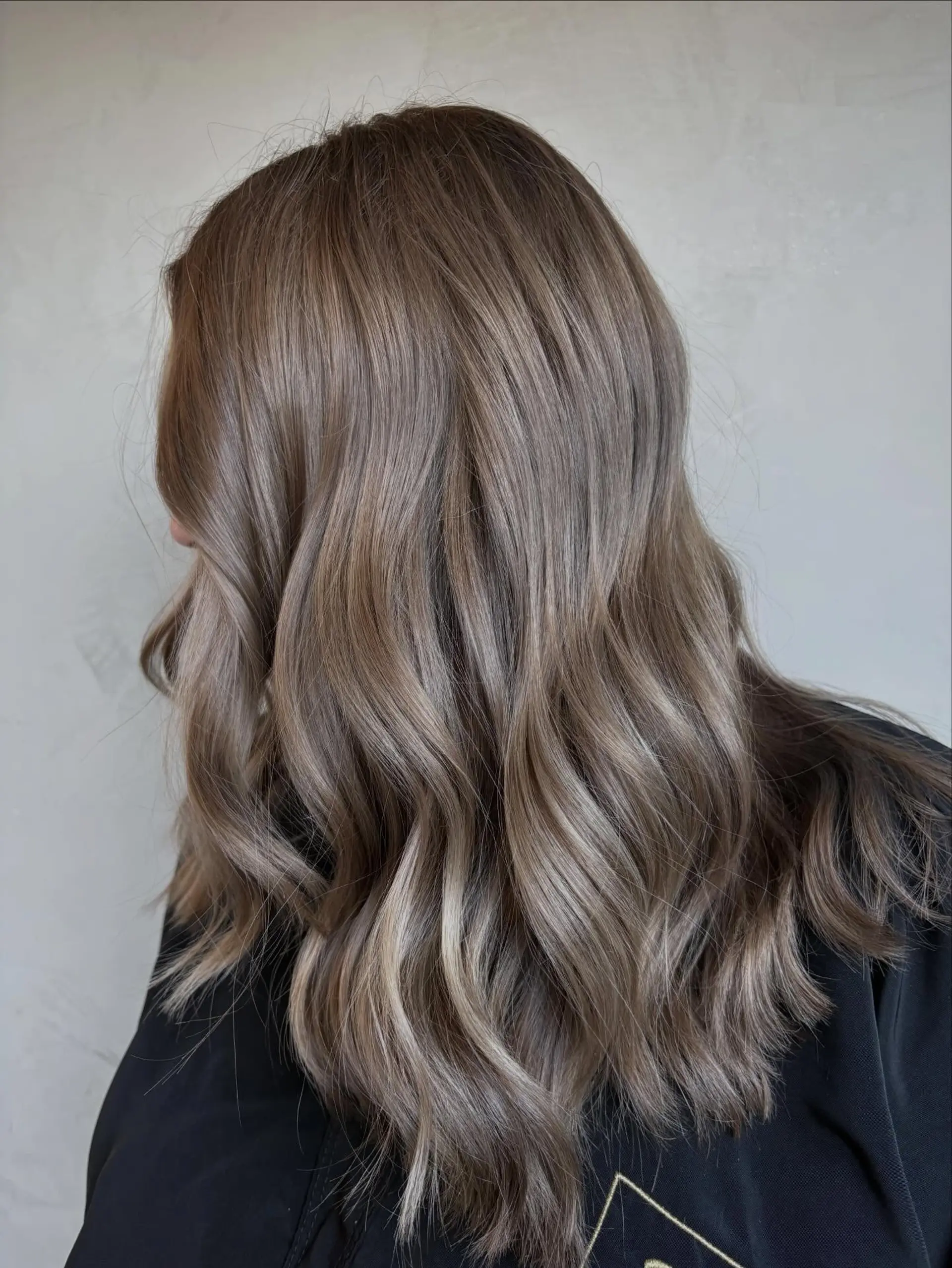 Long cool-toned ash brunette hair styled in loose, soft waves with seamless dimensional undertones. 1