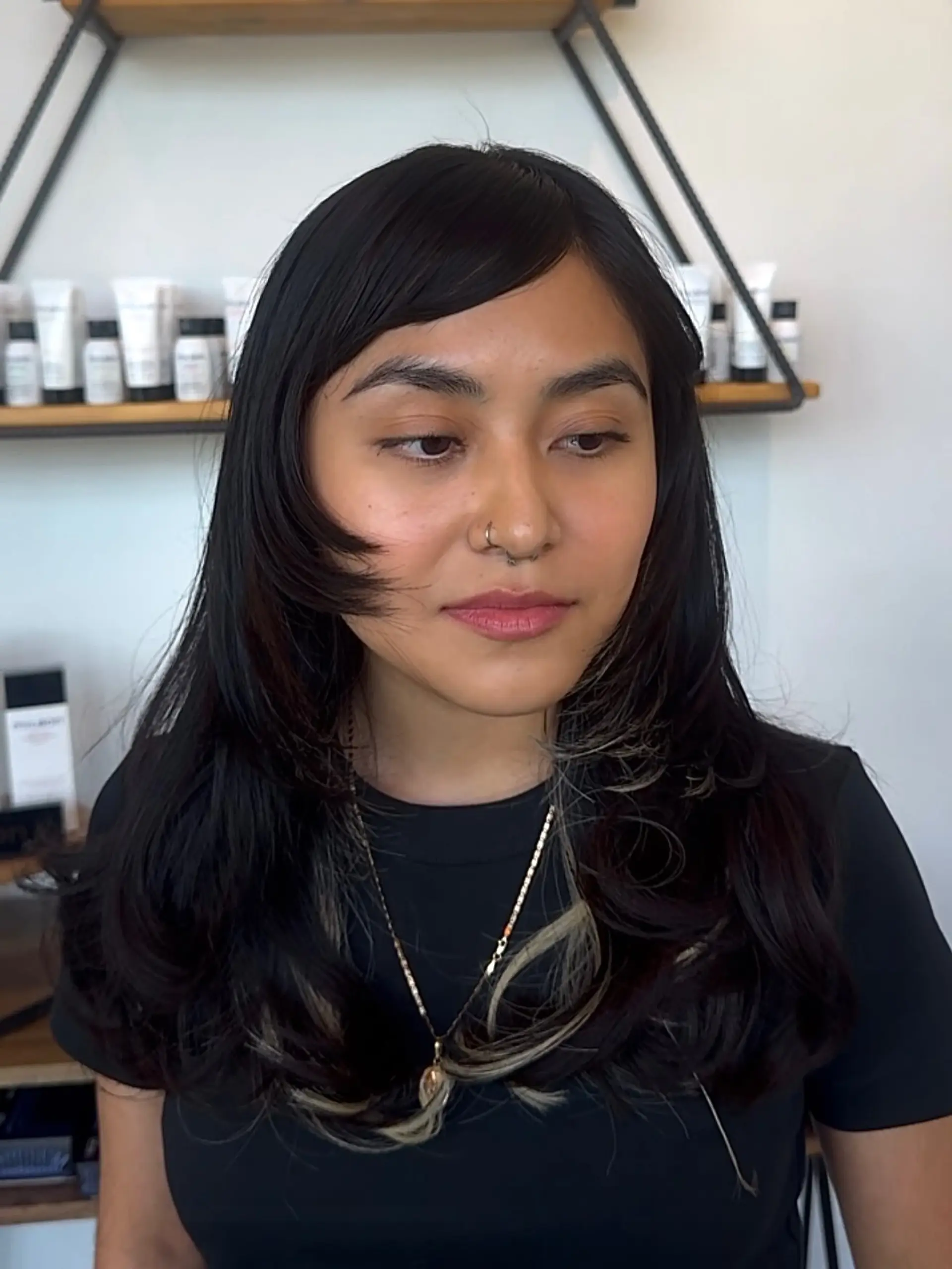 Long dark layered hair featuring side-swept bangs and soft ash blonde peekaboo highlights underneath. 1