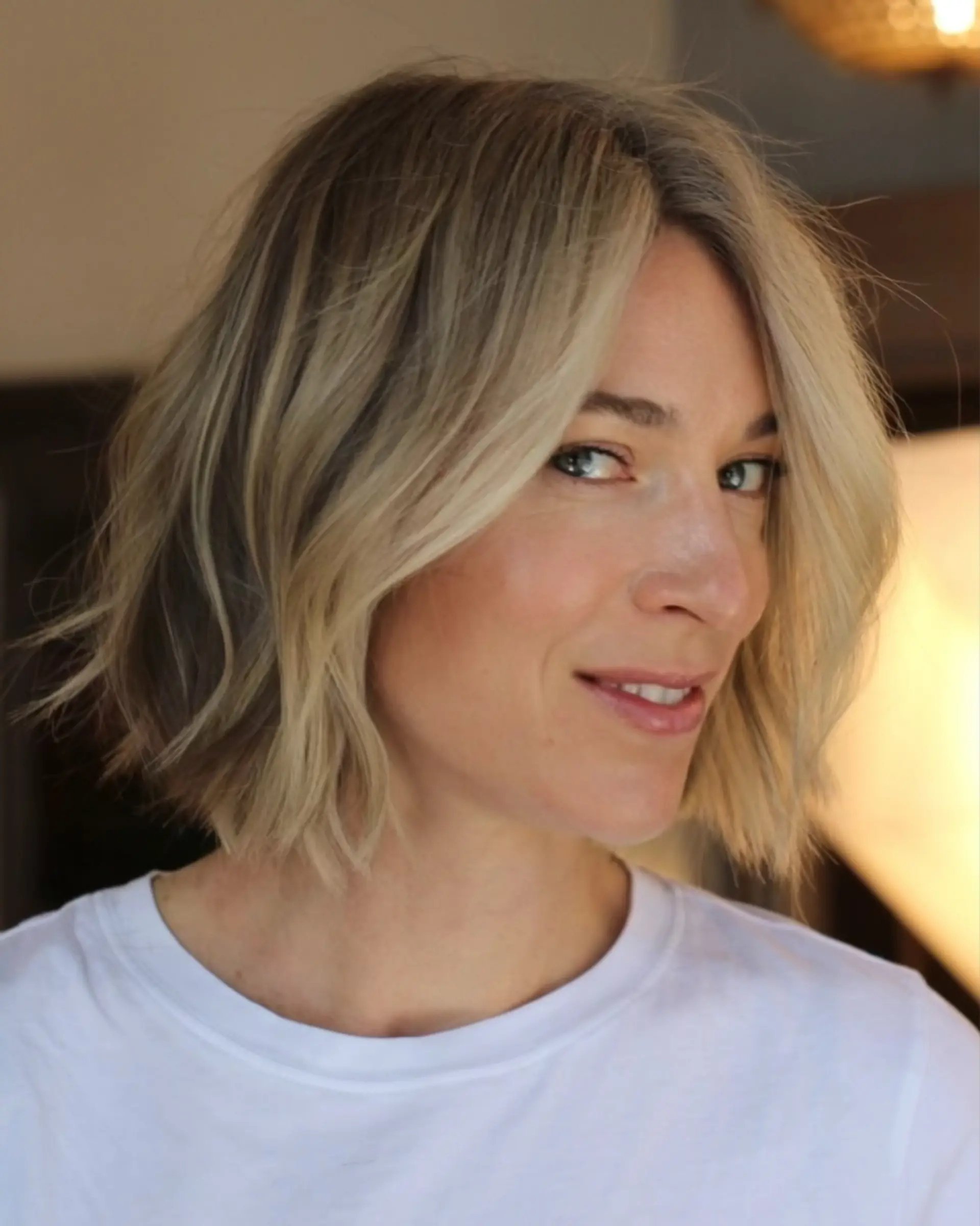 A chin-length textured bob styled with loose, undone waves and dimensional blonde coloring. 1