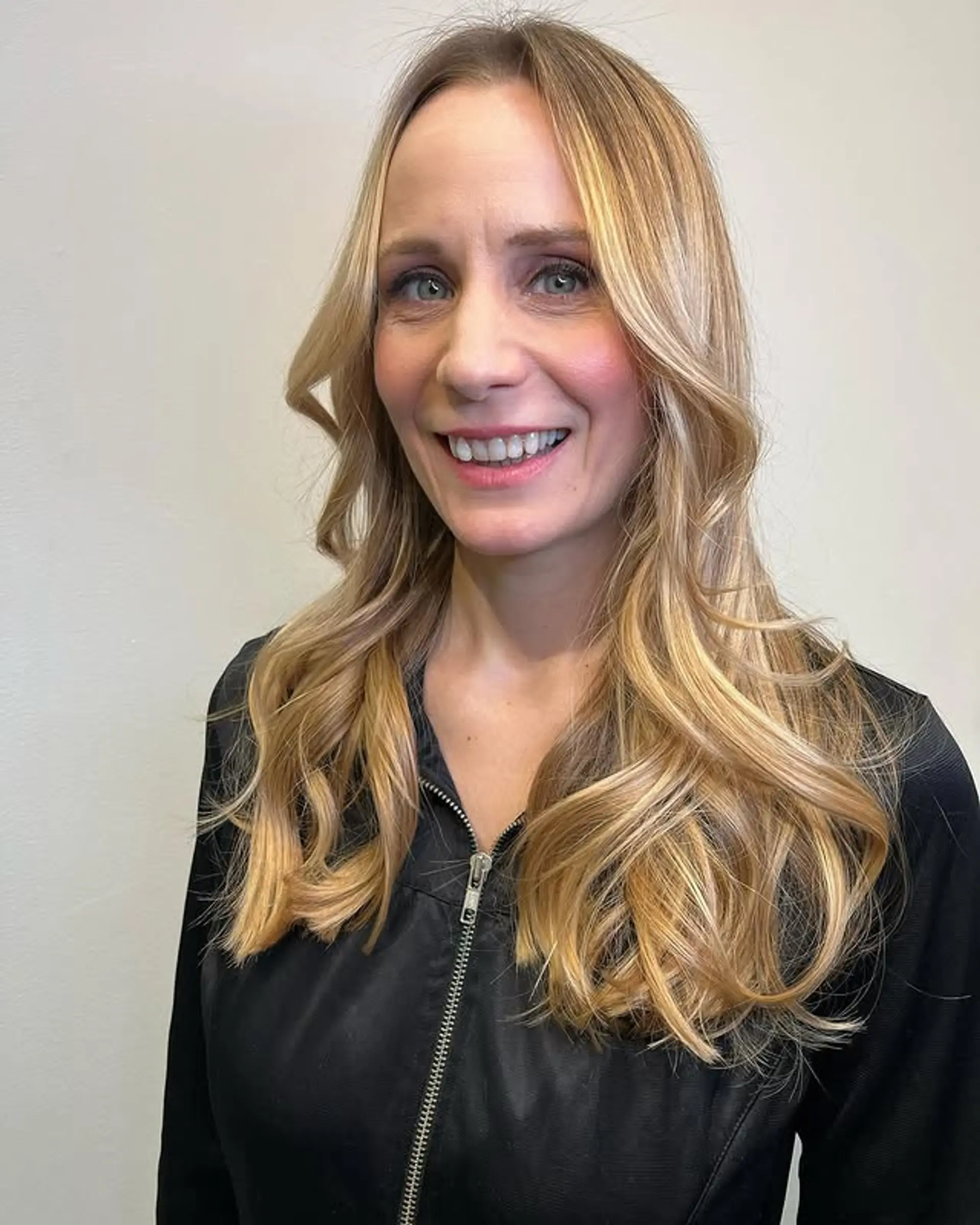 A long, wavy hairstyle with a sun-kissed blonde balayage and voluminous curls. 1