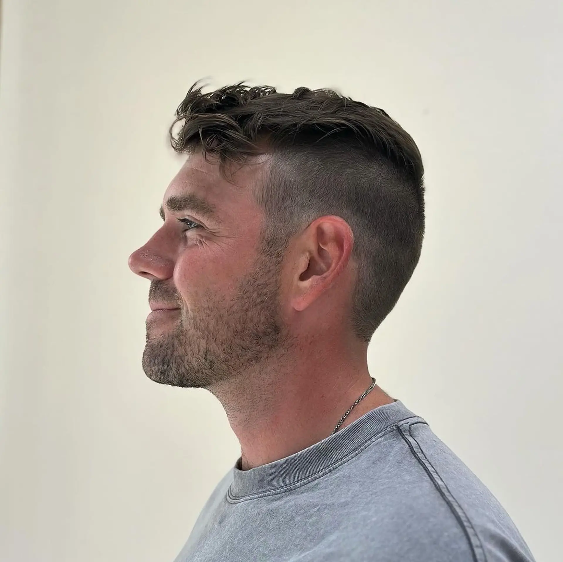 A short wavy hairstyle with an asymmetrical wave on top, contrasting neat sides, and a subtle low fade. 2